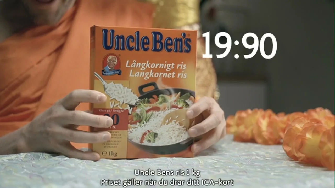 A person in an orange robe holds a box of Uncle Ben's rice on a patterned table, with a price overlay and text at the bottom.