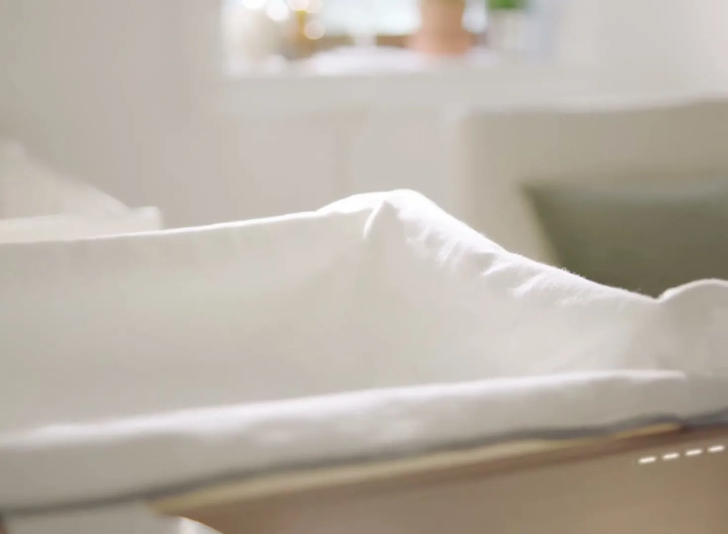 A mother in a floral scarf changes her baby's diaper on a changing table, then the camera pans down to reveal a storage drawer.