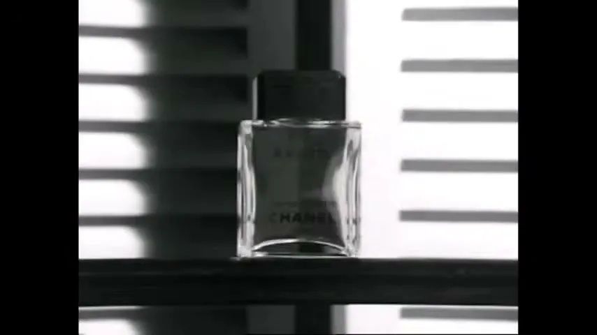 A man's hand places a bottle of "Egoiste" perfume on a balcony railing, then the shot zooms in on the bottle, which changes from black and white to color.