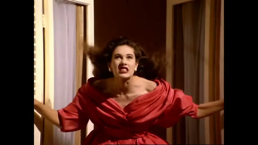 A woman in a red dress screams in frustration, her hands pushing against two white doors that close on her.