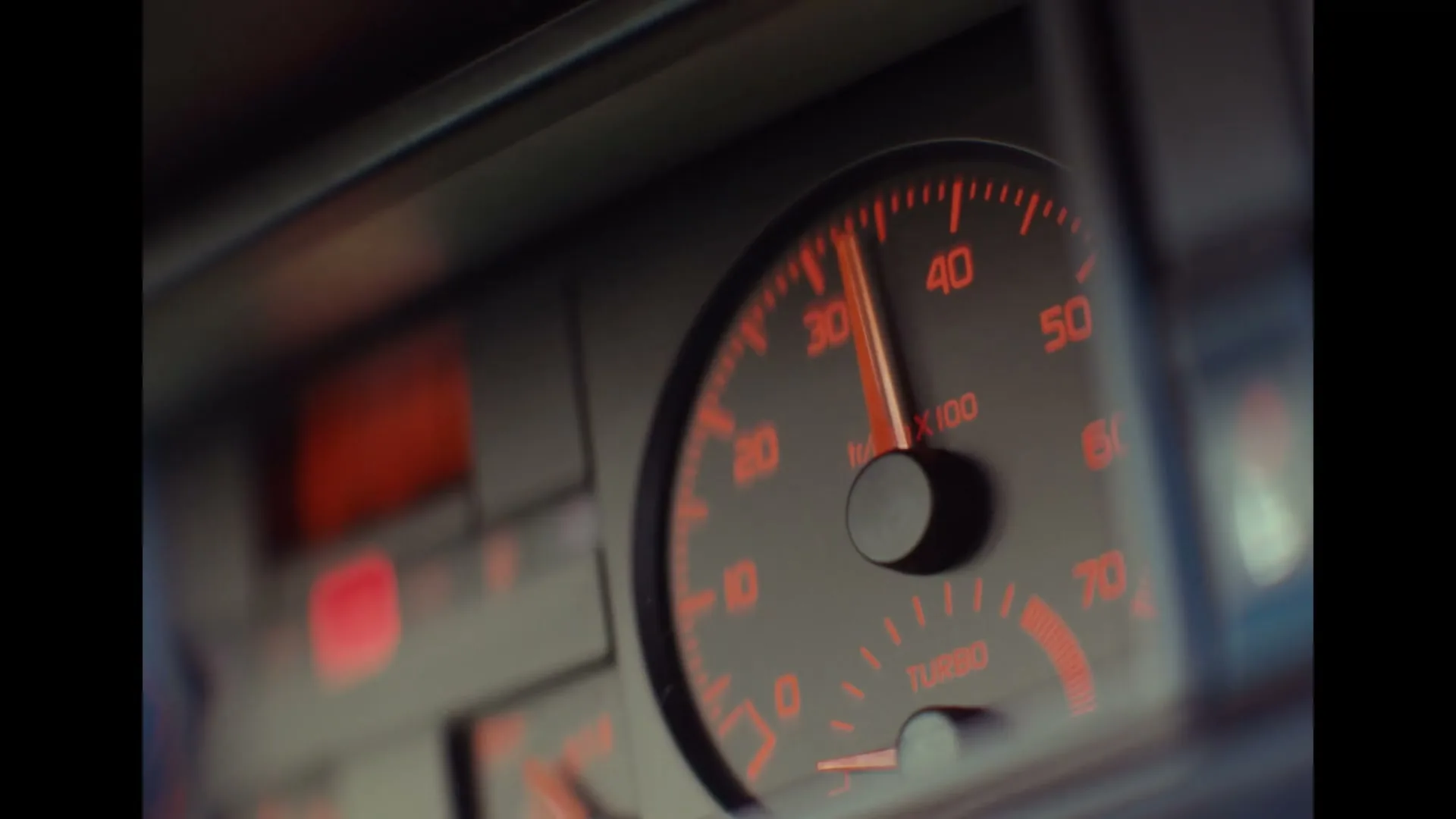 A close-up shot of a car's dashboard, showing the speedometer with a red needle rapidly increasing, indicating acceleration.