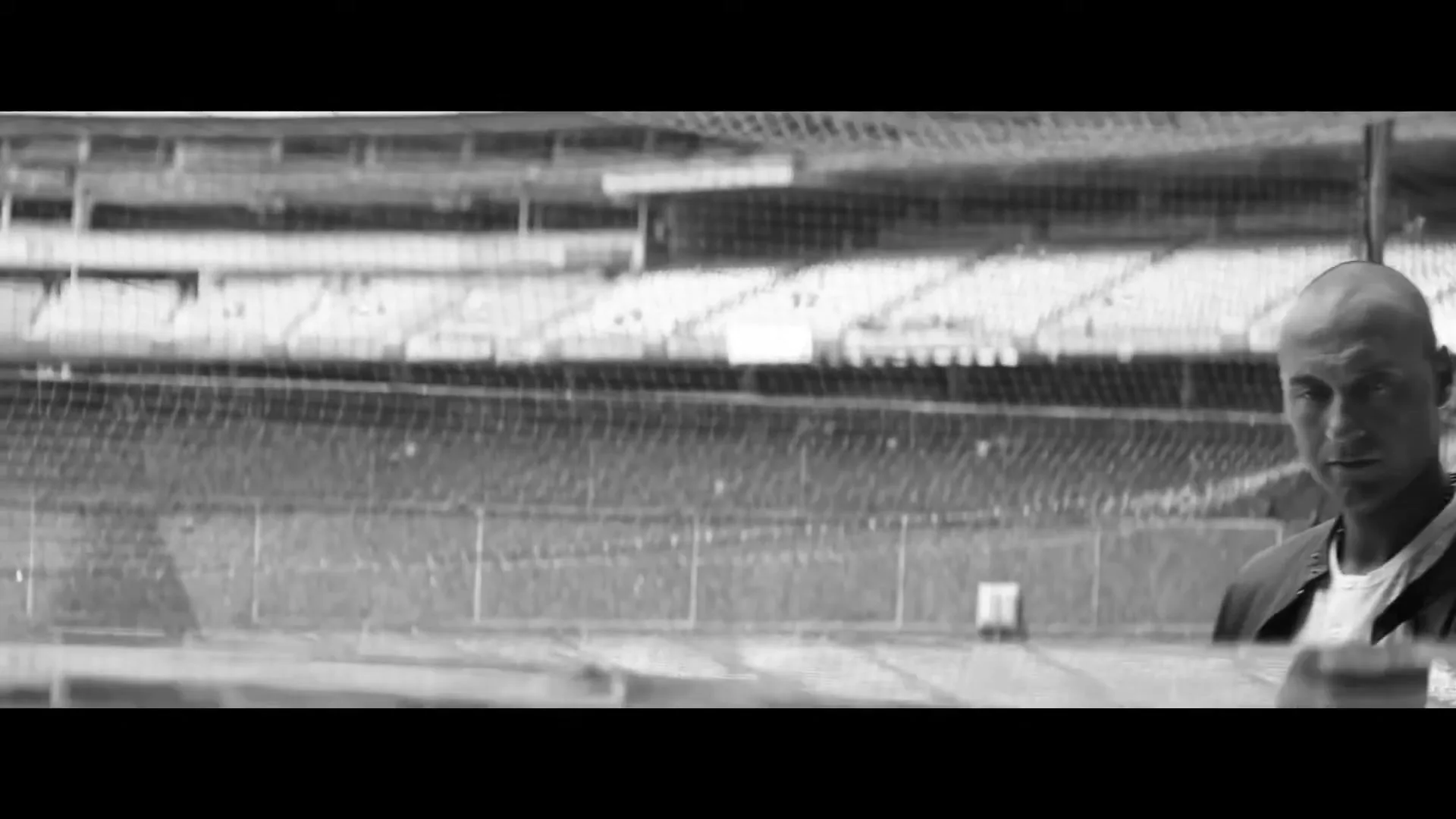Derek Jeter, a bald male in his 30s, wearing a jacket and t-shirt, looks directly at the camera from a baseball dugout, with an empty stadium in the background.
