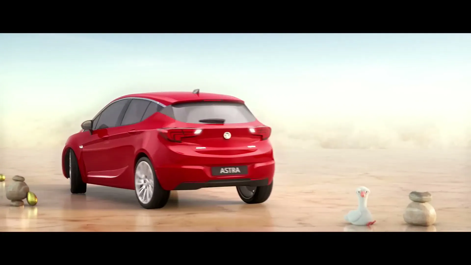A red Vauxhall Astra car is shown in a wide shot, reversing on a sandy plain with a white goose and golden eggs, as the camera slowly zooms in.