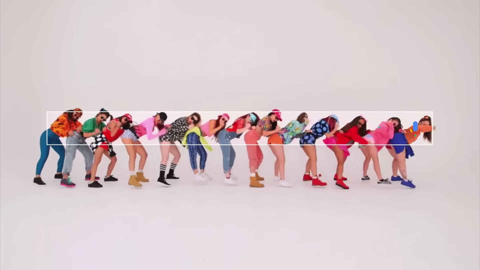 A line of diverse young women in colorful, mismatched outfits and sunglasses dance in a studio with a white background.