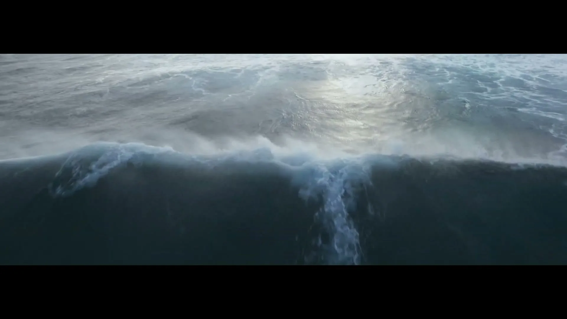 An aerial shot shows a surfer riding a large wave in the ocean, with the sun reflecting on the water's surface.