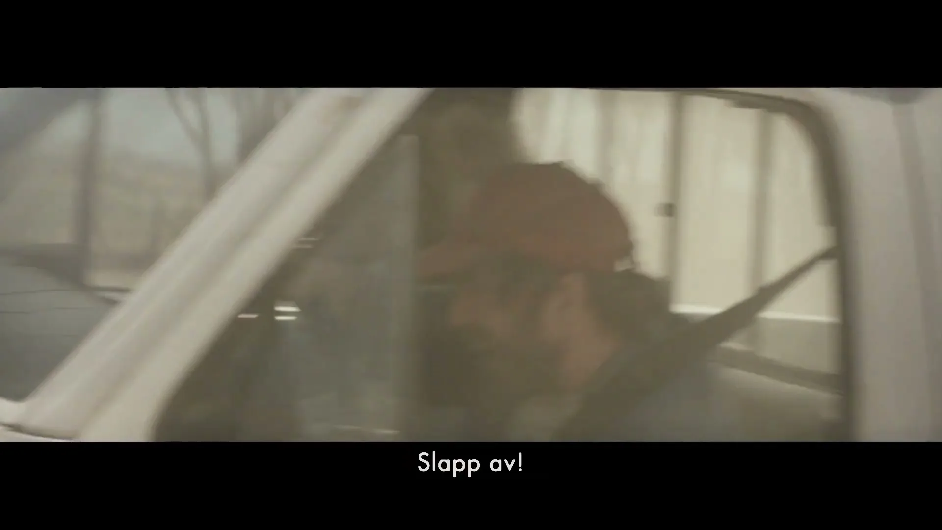 A man in a cap and a woman are seen inside a white pickup truck, with the man trying to calm the woman down during a chaotic moment.