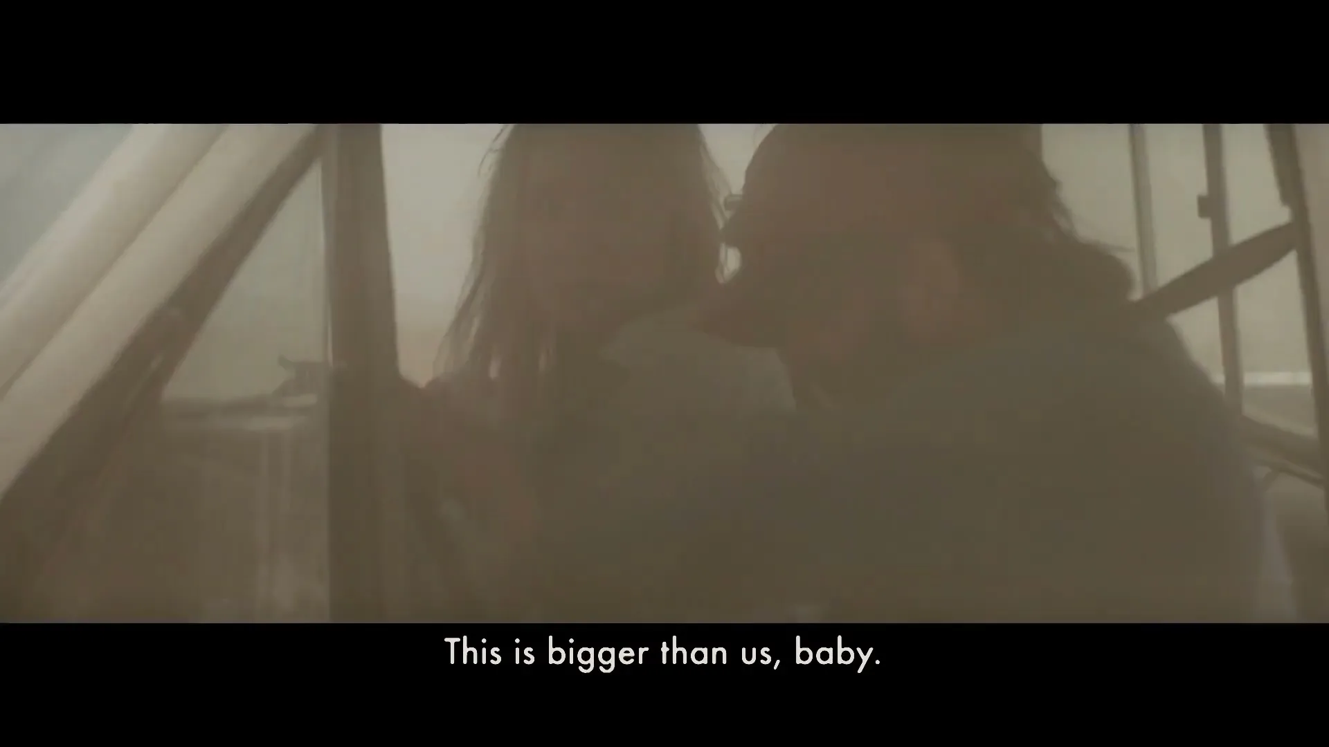 A man and a woman are inside a white pickup truck, looking out at a massive tornado forming in the distance under a cloudy sky.