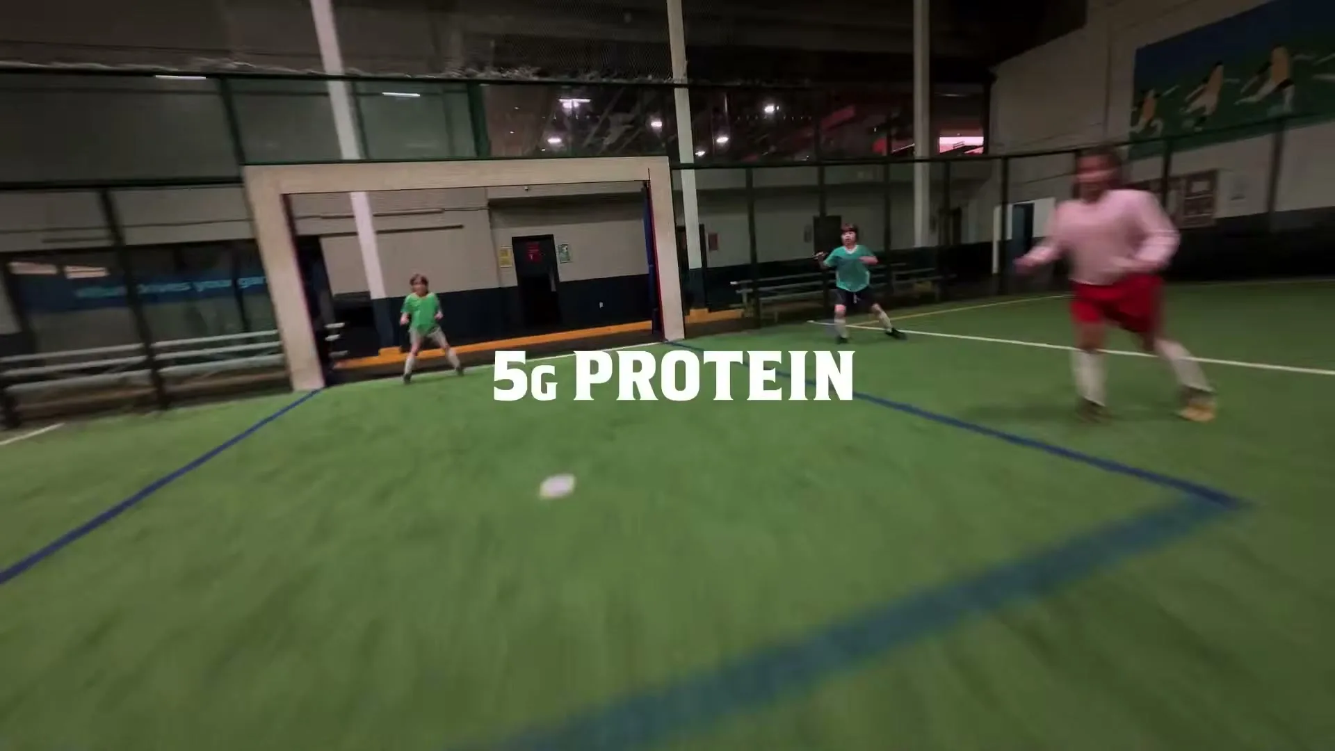 A group of kids play indoor soccer on a green turf field, with "5G PROTEIN" text overlaid on the screen.