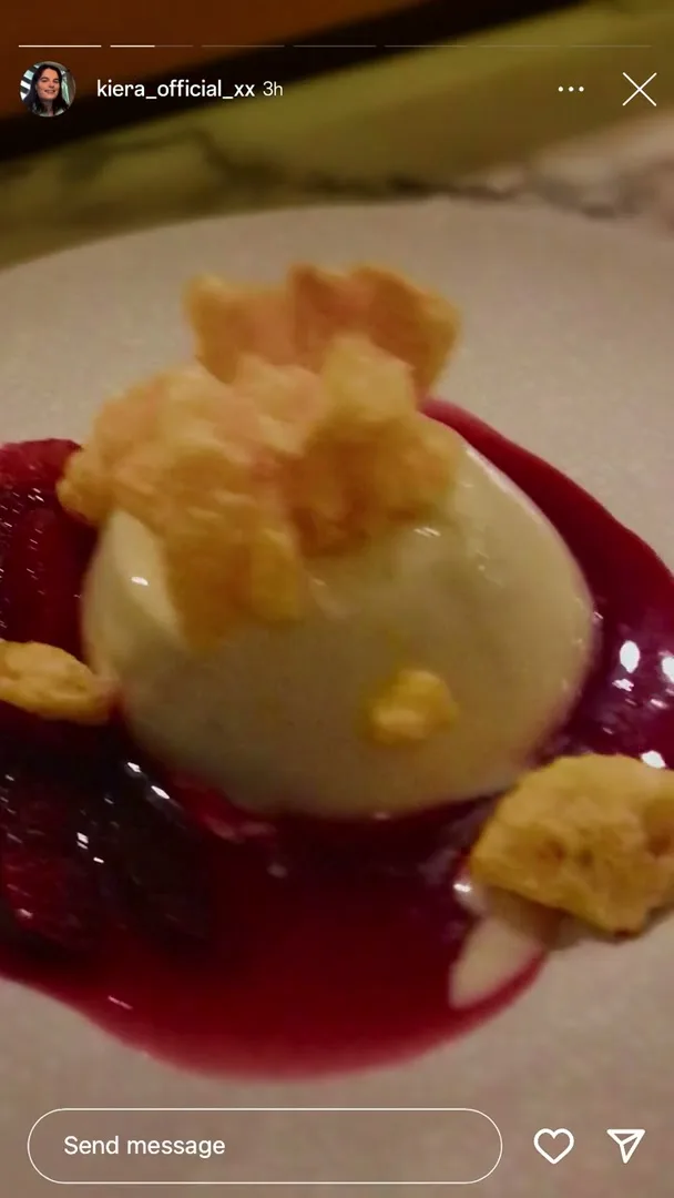 A close-up shot of a white dessert with red sauce and crunchy toppings, presented on a white plate, filmed as a phone screen recording.