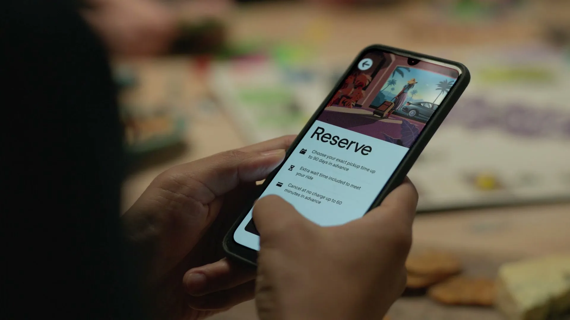A person's hands hold a smartphone displaying the Uber app's "Reserve" screen, then tapping to input a pickup location, in an interior setting.