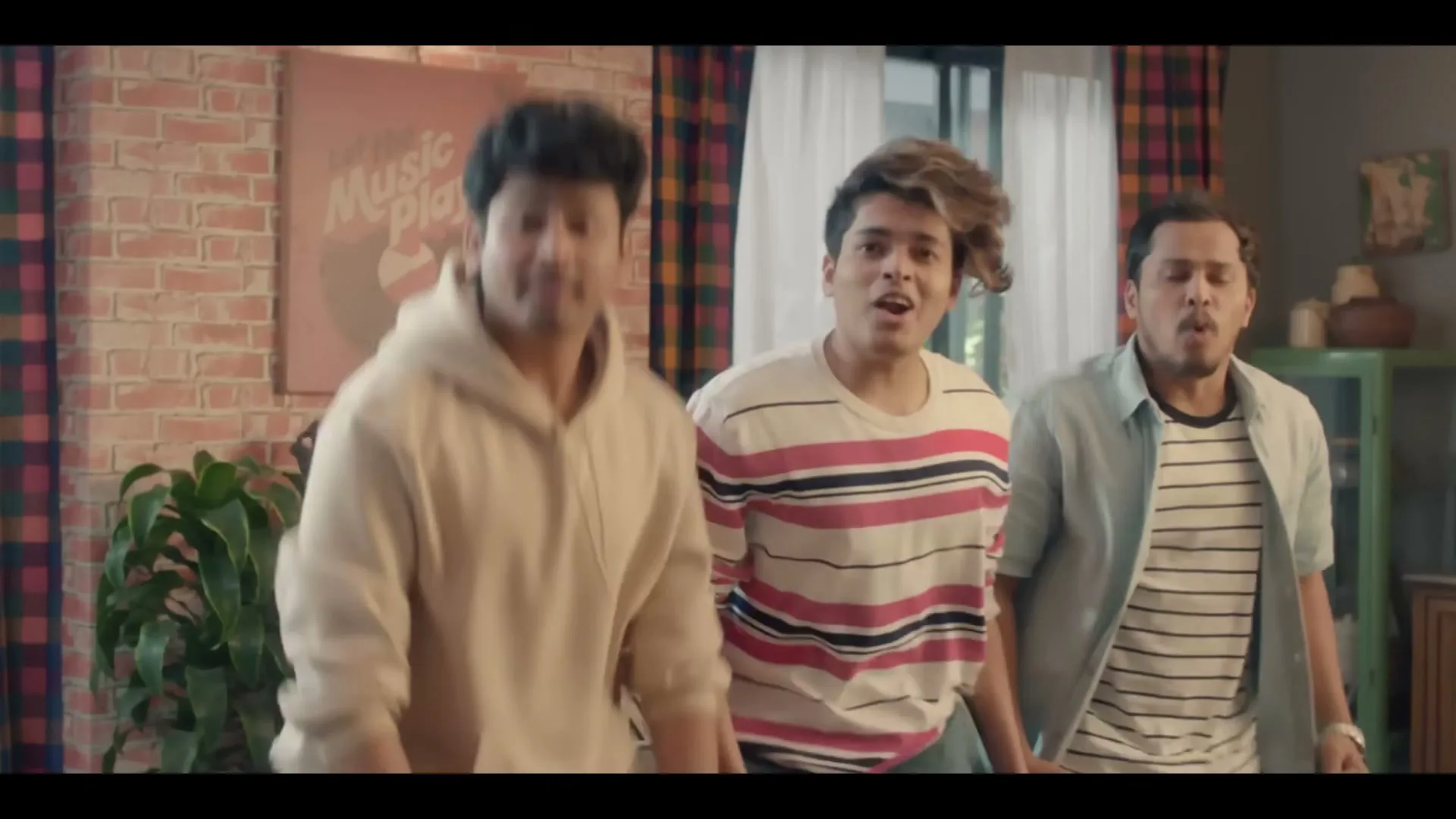 Three young men in casual clothes are surprised while sitting on a couch in a living room, then stand up and look forward.
