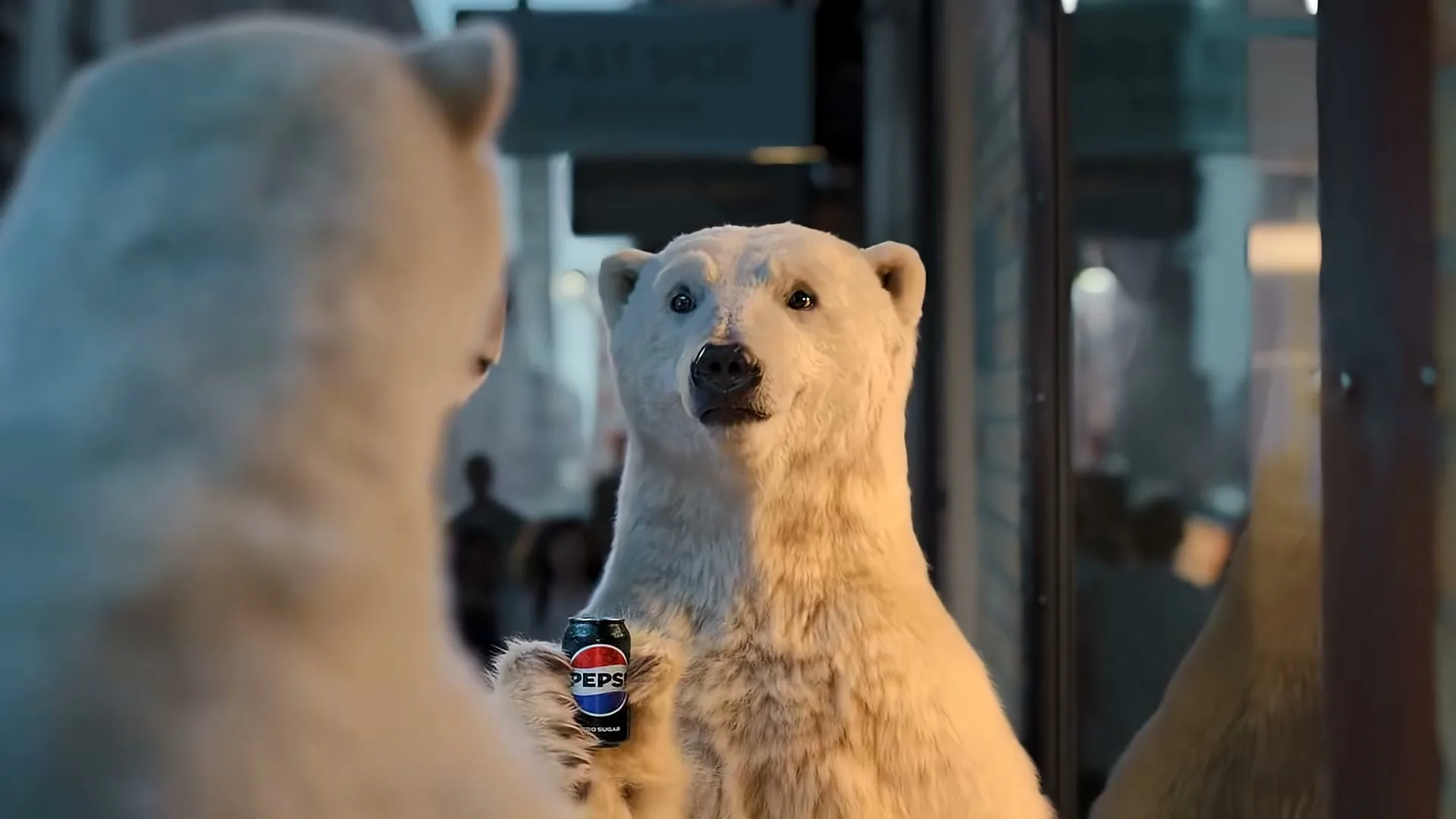 A polar bear looks at its reflection in a window, holding a Pepsi can, in a city at night.