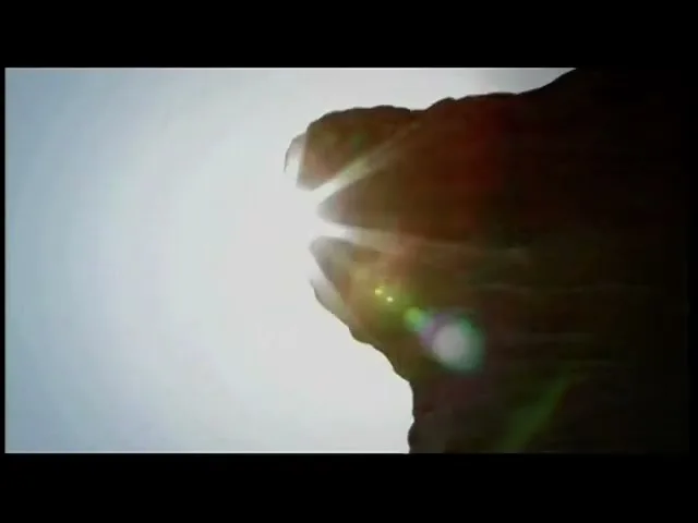 The sun peeks over a silhouetted cliff edge, creating a bright lens flare against a clear sky.