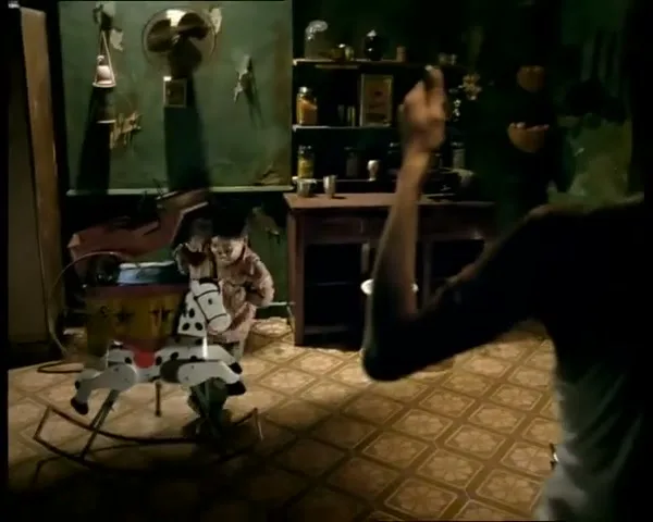 A woman in silhouette raises her arms, then a child on a rocking horse is revealed in a dimly lit, cluttered room.