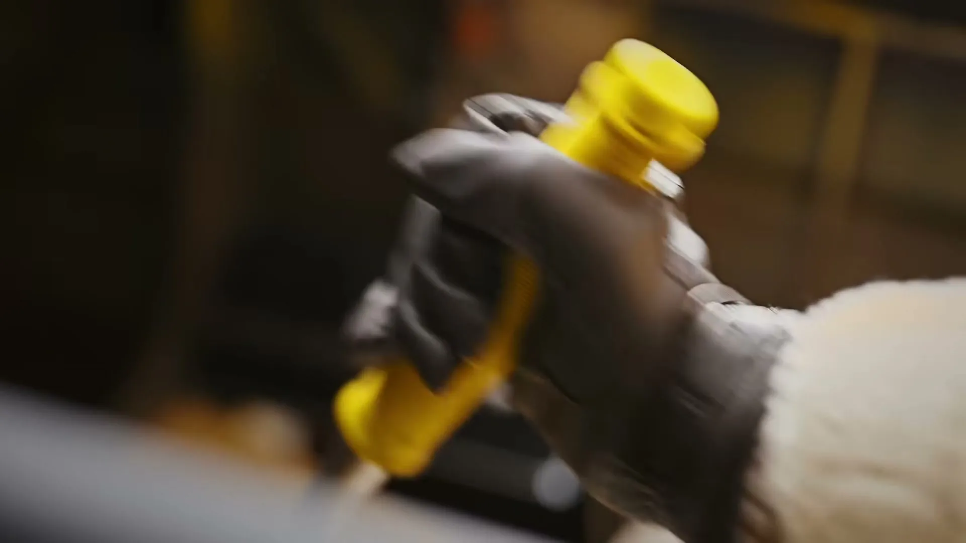 A gloved hand holds a yellow object, moving quickly in a blurred, close-up shot.