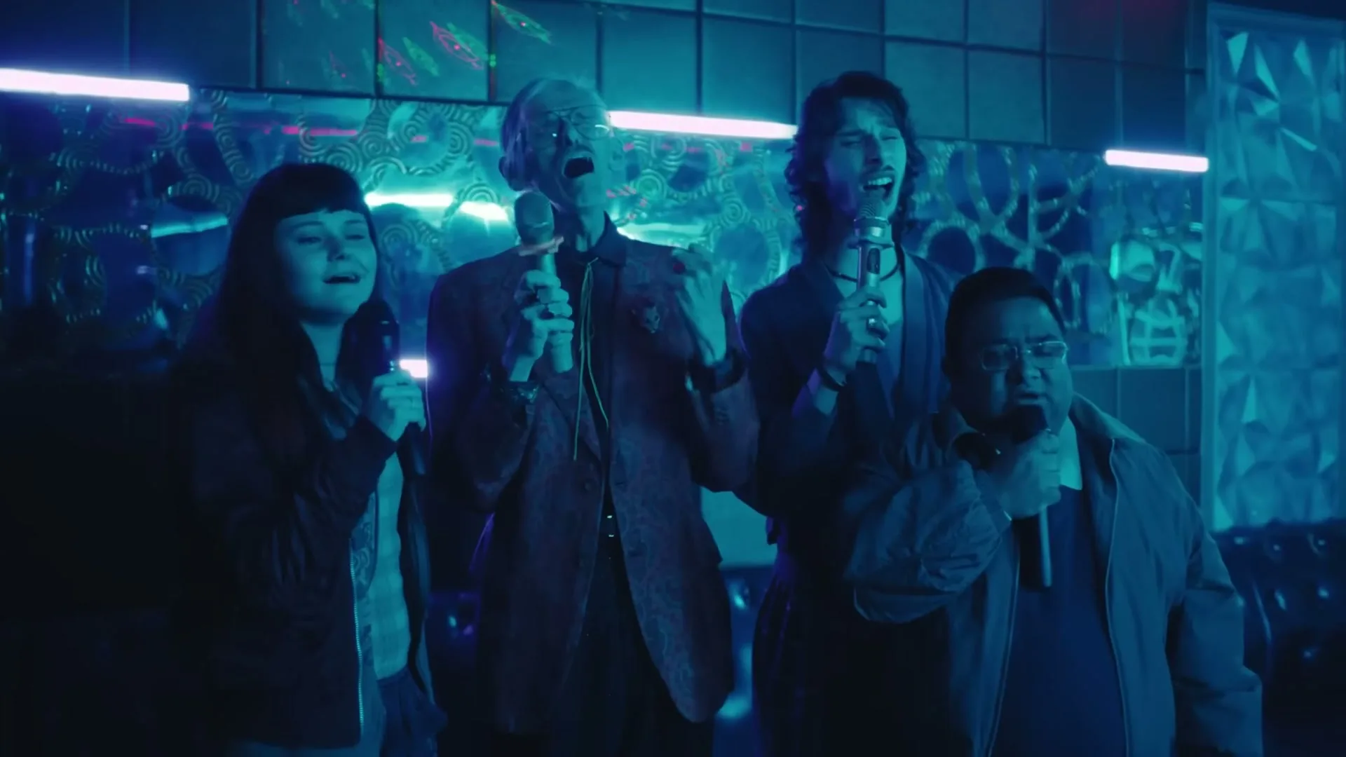 Four diverse friends, two men and two women, sing karaoke with passion and enthusiasm in a dimly lit, neon-blue karaoke bar.