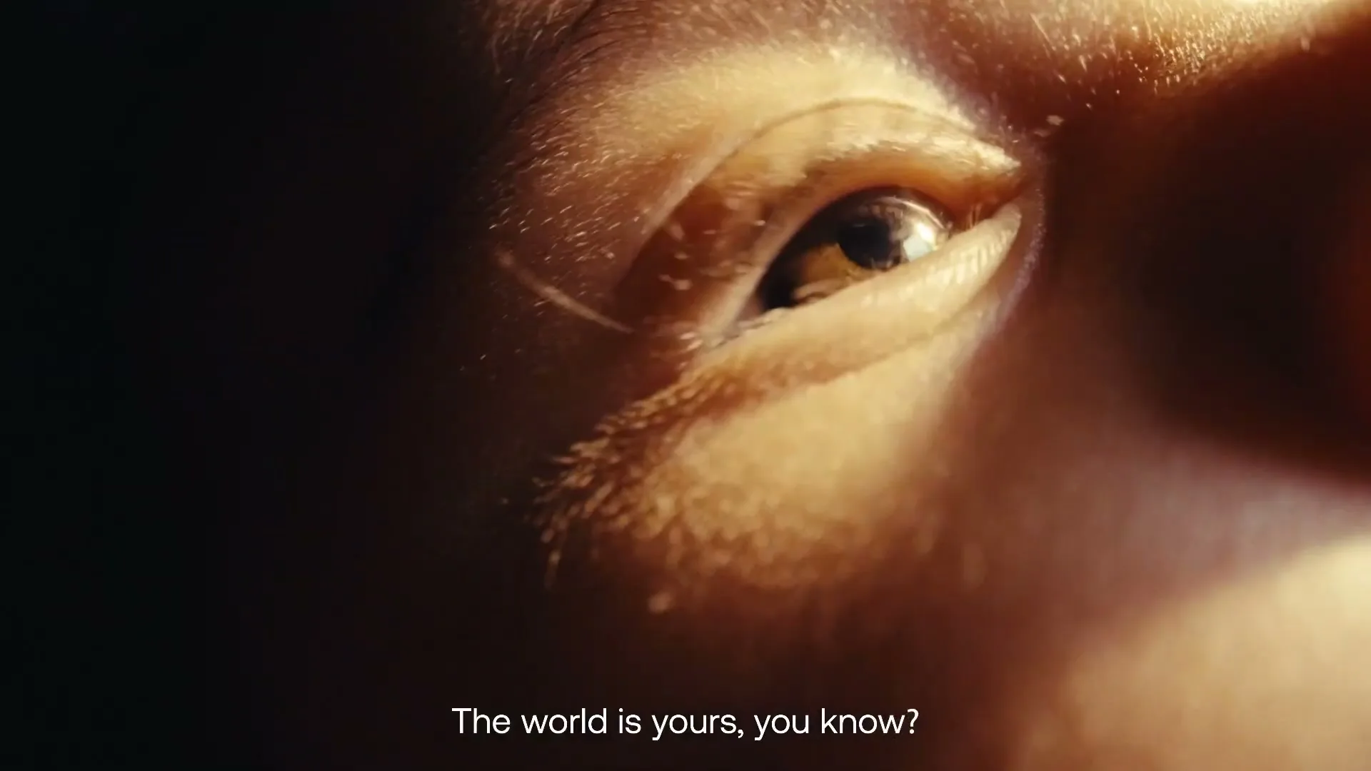 A child's eye, with light reflecting in the pupil, is shown in an extreme closeup, with a dark background.