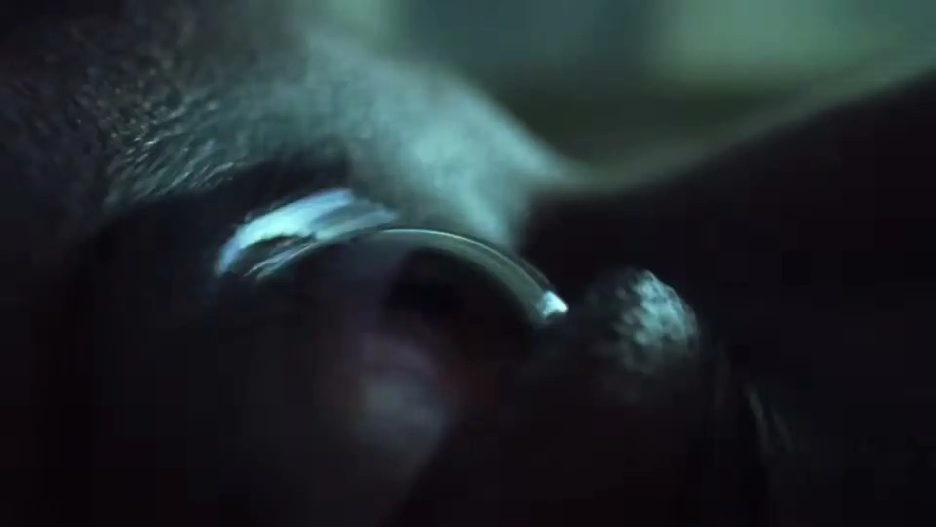 A person's eye is shown in extreme closeup, with a contact lens being inserted, in a dark, intimate setting.