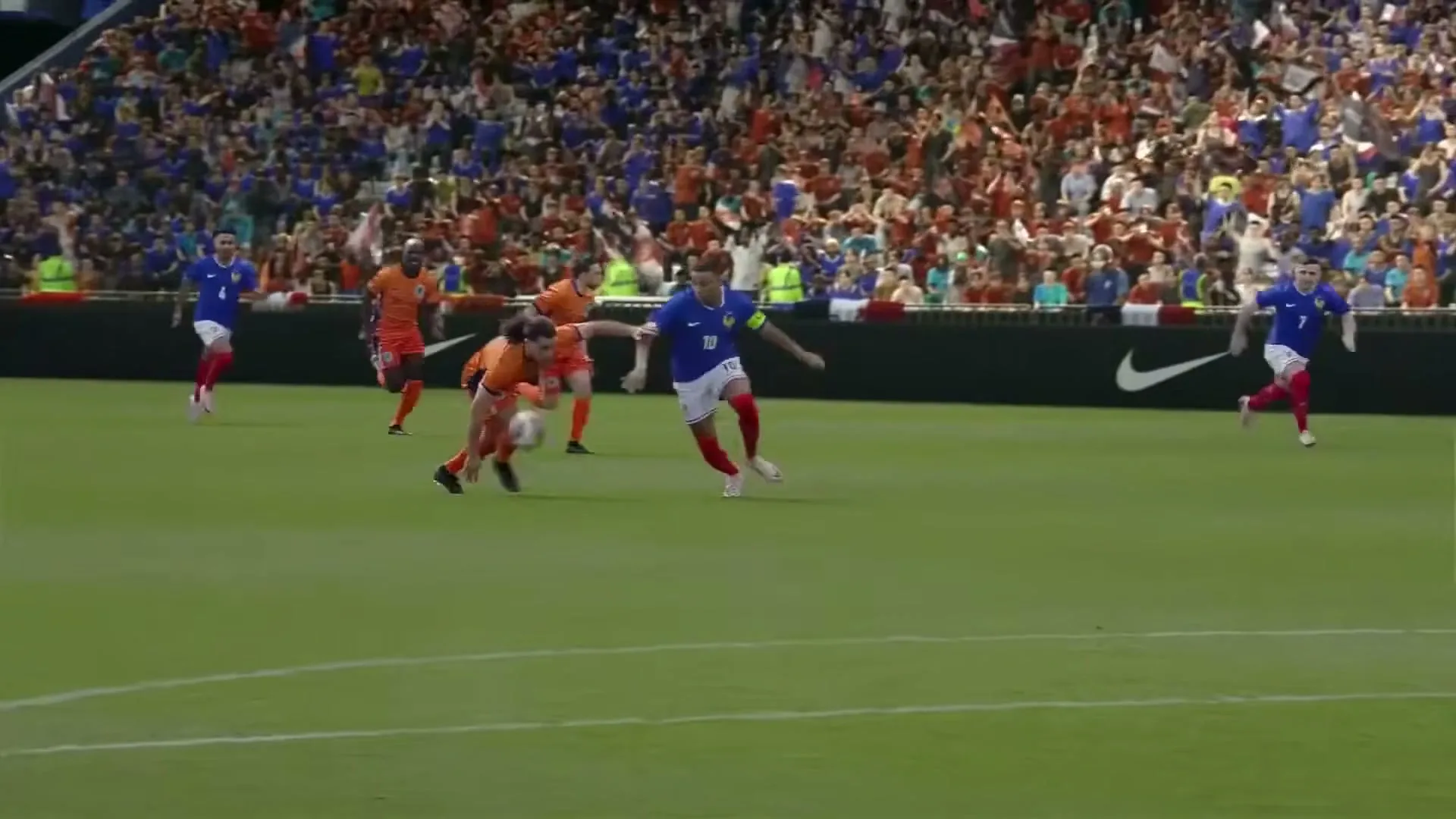 Soccer players in orange and blue uniforms compete on a green field, with a large crowd visible in the background.