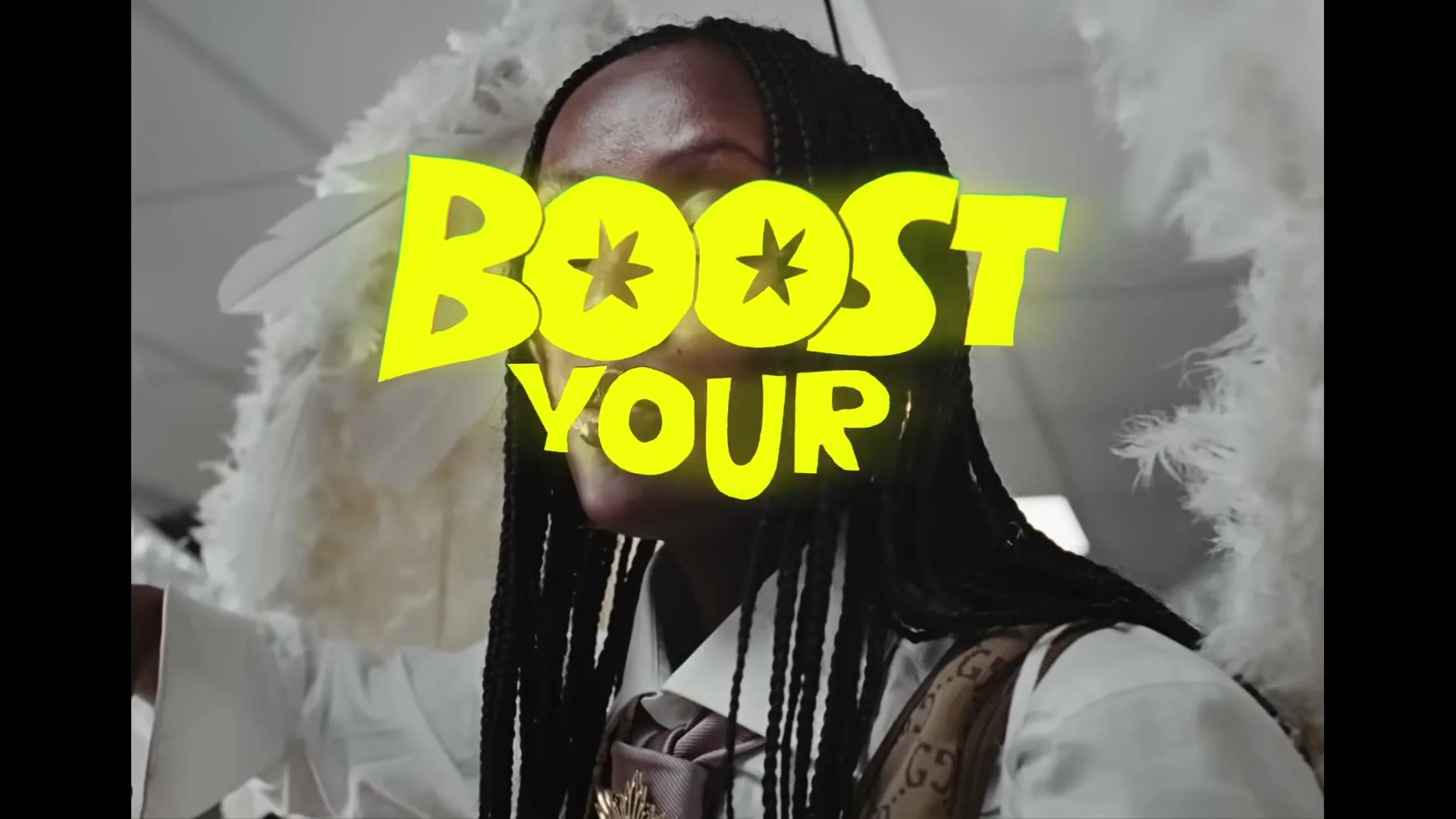 A person with braided hair and a white shirt with a tie and vest, wearing large white feathered wings, is seen from the chest up, with glowing yellow text "BOOST YOUR" superimposed over their face.