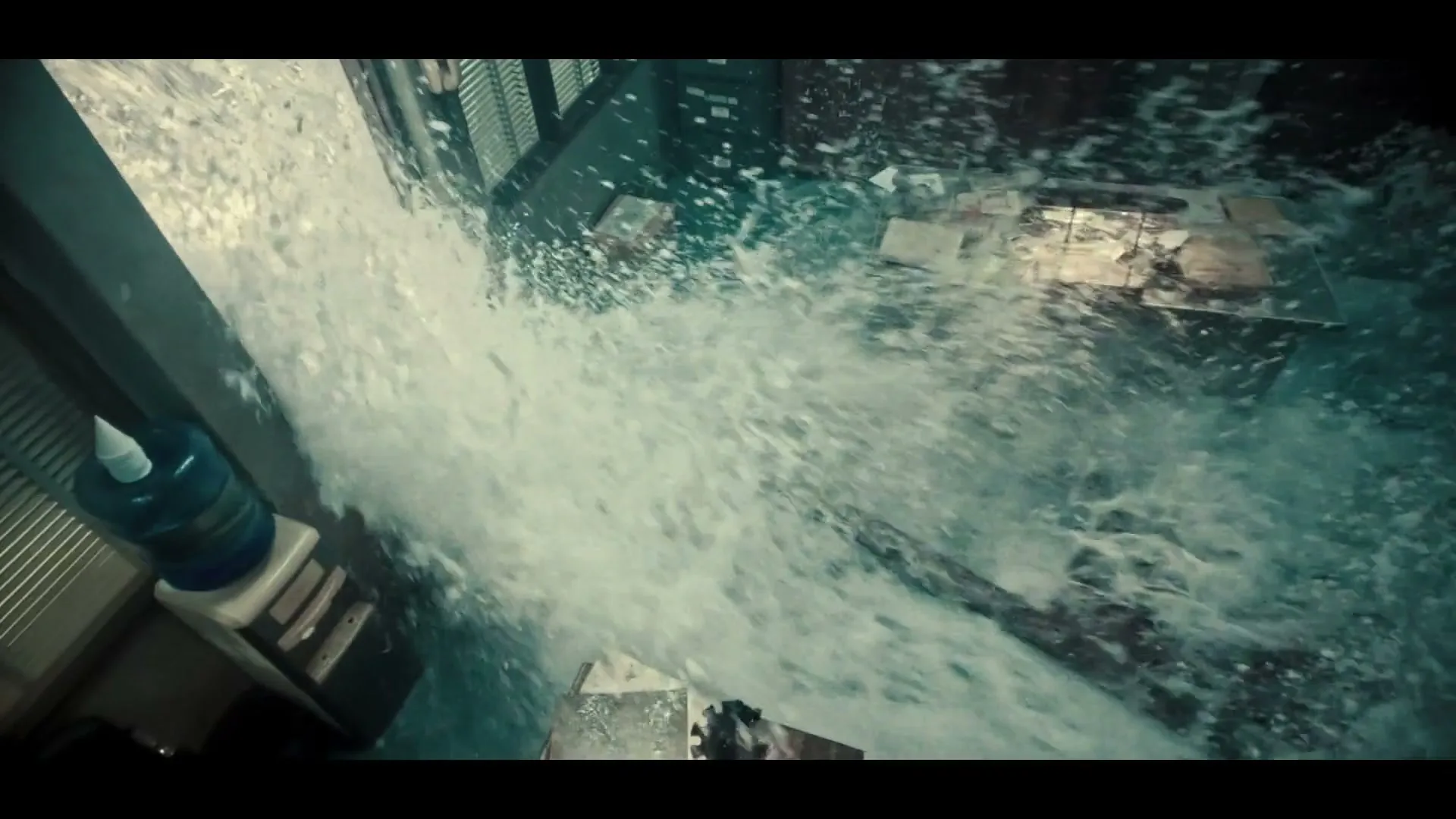 A wide shot shows an office interior being flooded with water, with a desk and water cooler visible.