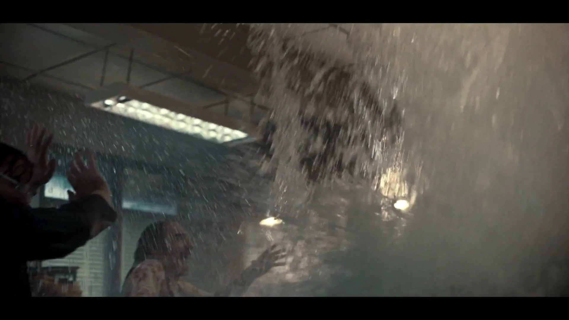 Two men are submerged in water, with one man in a suit raising his hands as a large splash of water erupts in an office.