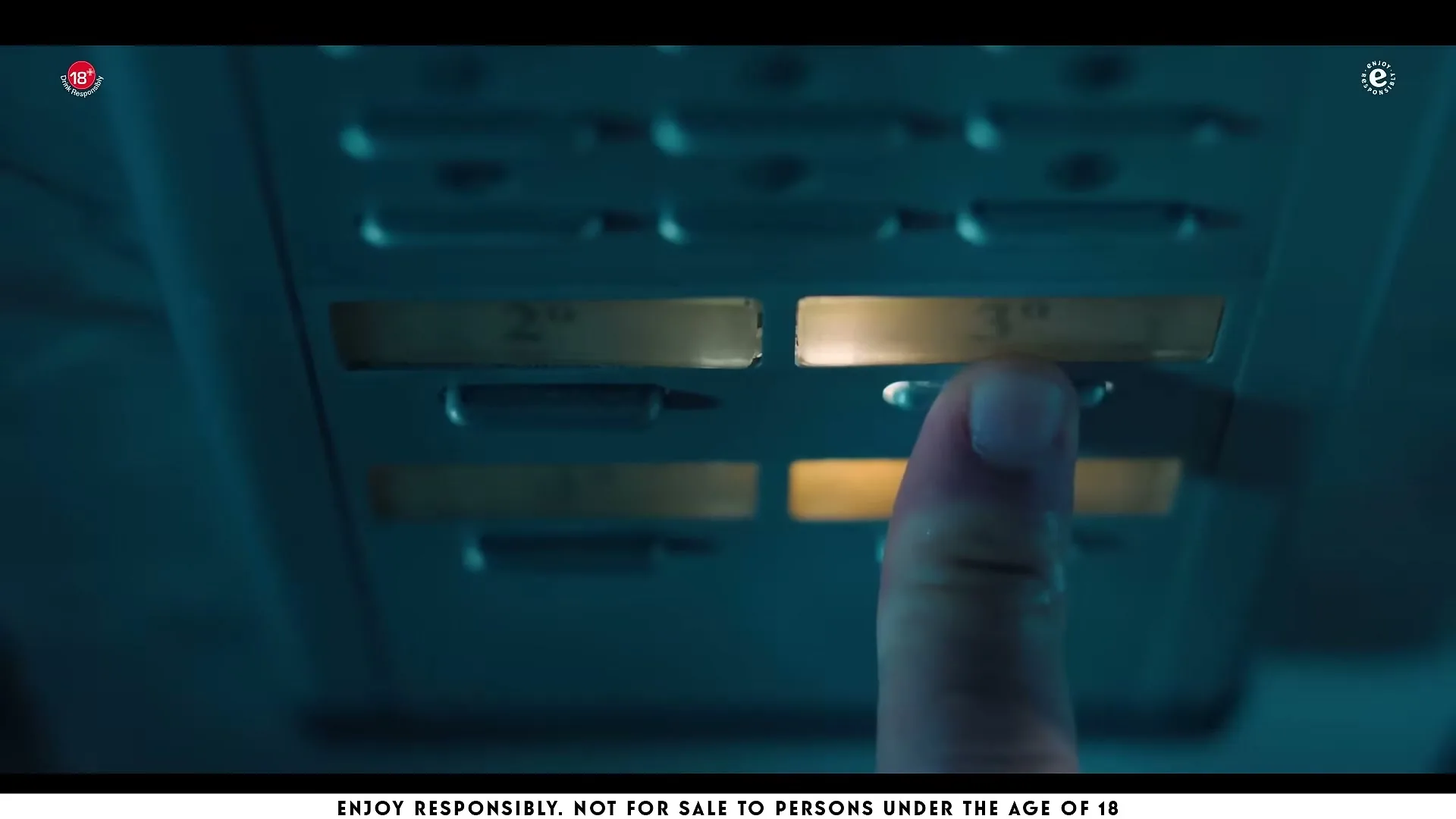 A person's finger presses a button on an overhead panel in a dark, blue-lit interior, possibly an airplane or bus.
