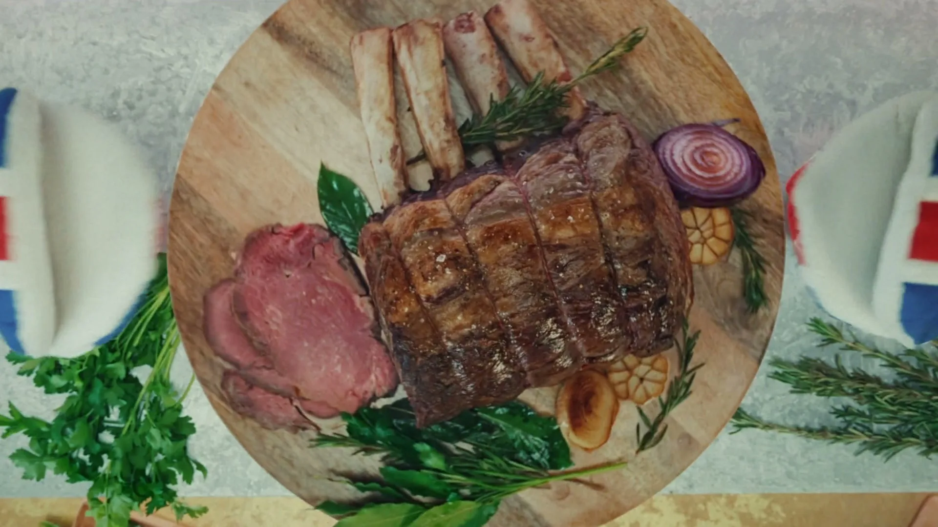 An overhead shot of a roasted beef joint with sliced meat, herbs, and onions on a wooden board, surrounded by festive decorations.