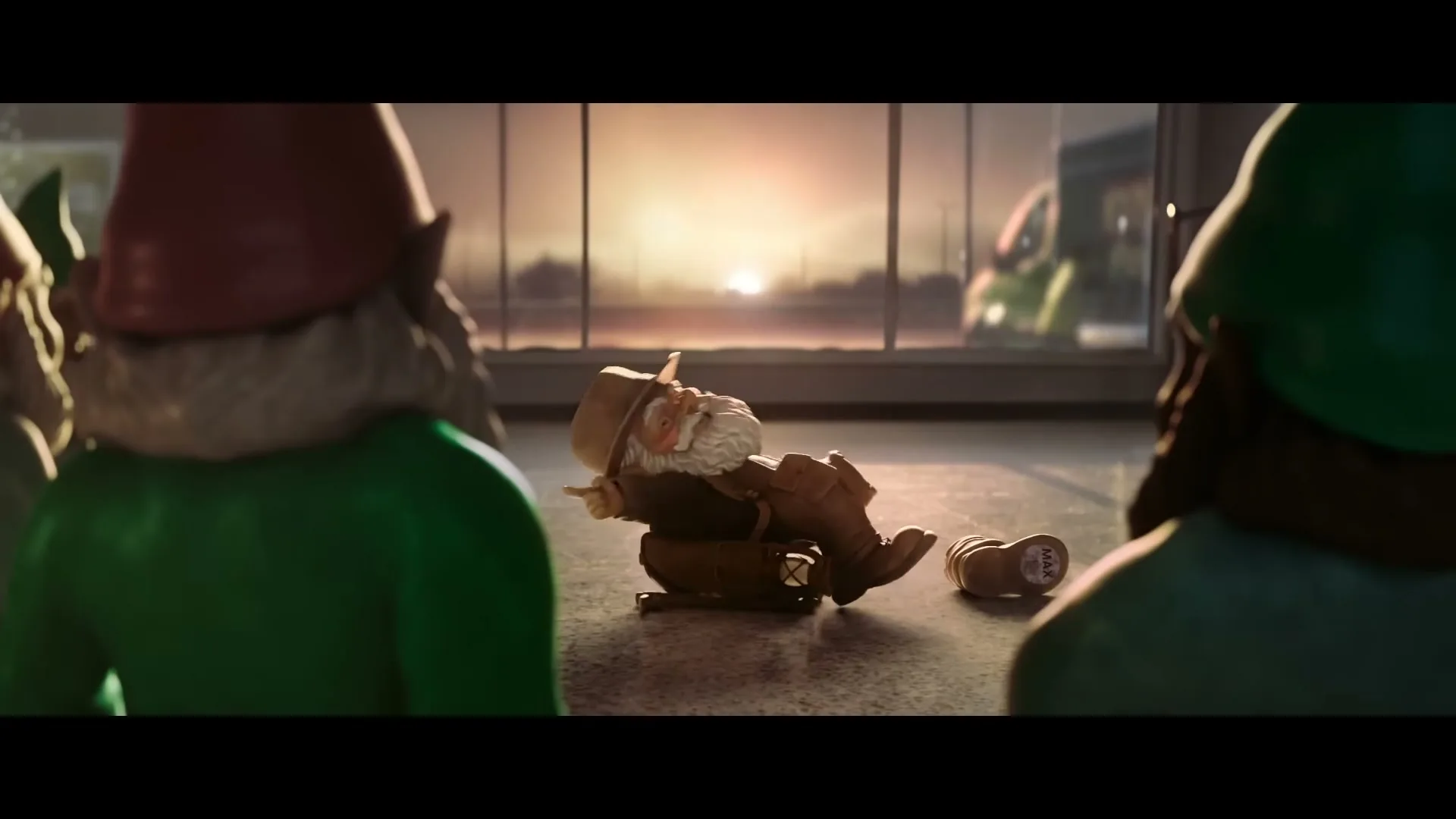 A gnome in a brown hat and jacket falls over, surrounded by other gnomes, in an airport terminal at sunset.