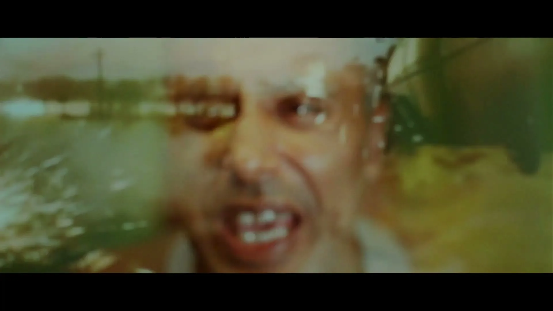 A man's face is seen through a blurry, distorted lens, with a bright light in the foreground, creating a sense of panic.