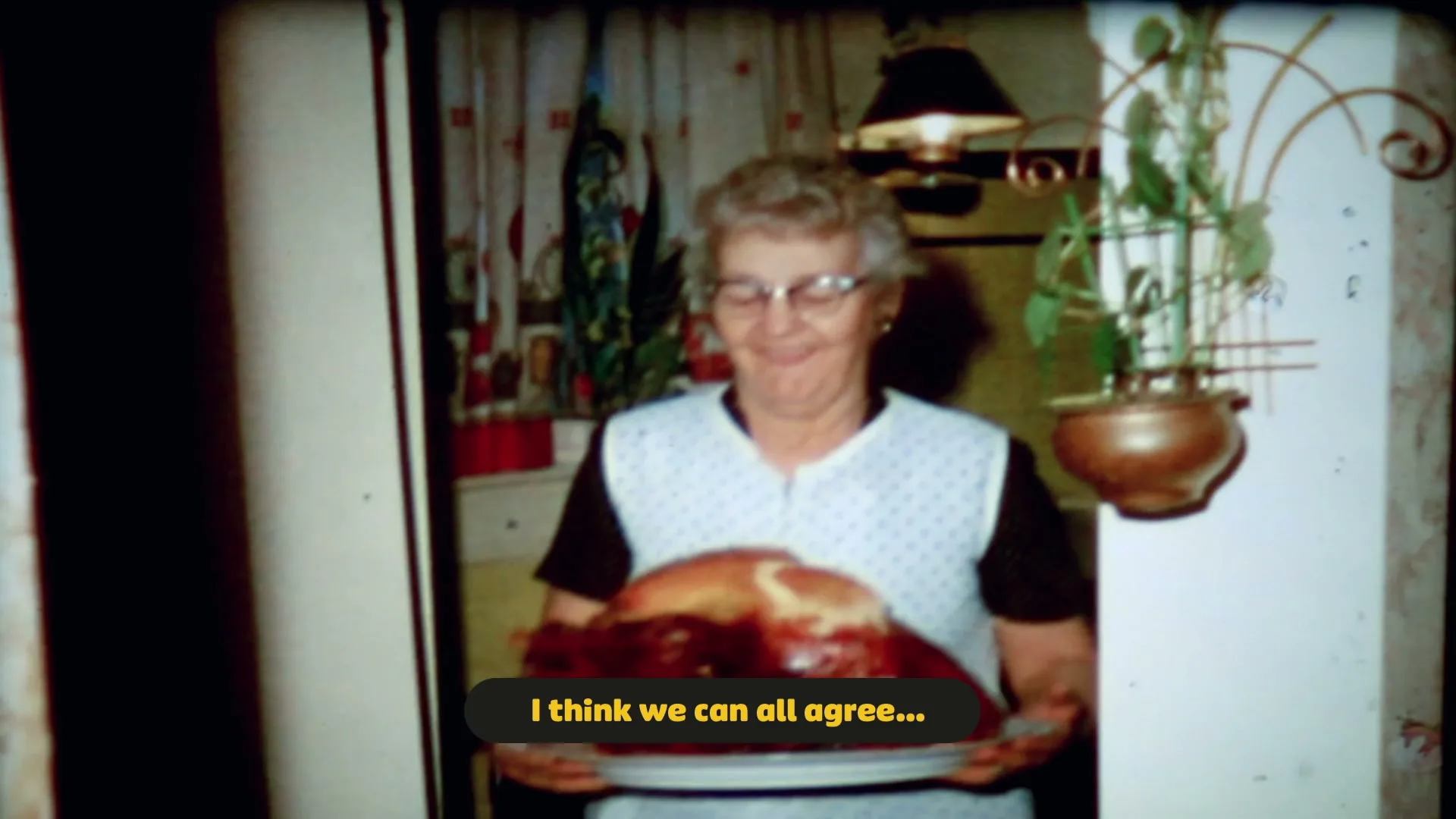 An elderly woman in glasses and an apron smiles while holding a large roasted turkey on a platter in a vintage-style kitchen.
