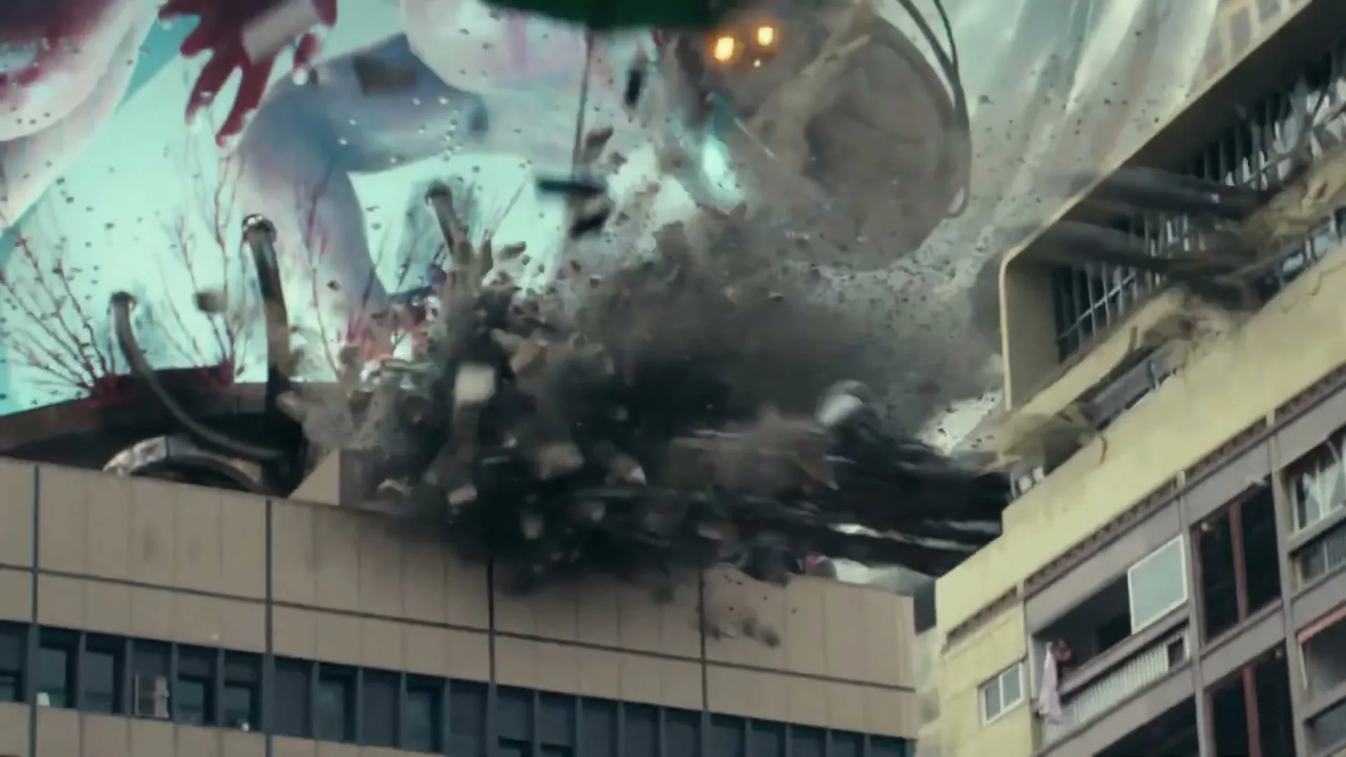 A giant monster's tentacles smash into the top of a building, causing debris and dust to explode outwards in a chaotic urban scene.