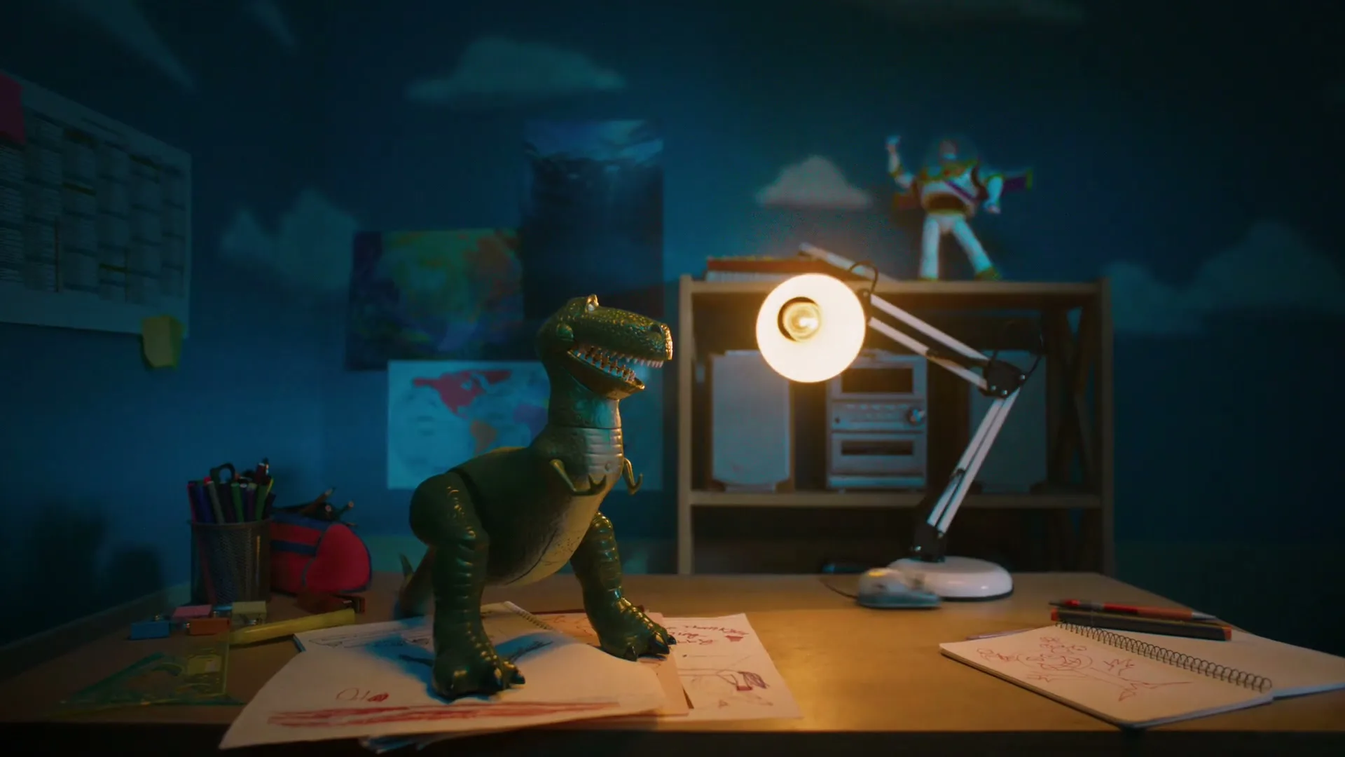 A green Rex dinosaur toy stands on a desk with drawings, a lamp, and a Buzz Lightyear toy in a child's bedroom at night.