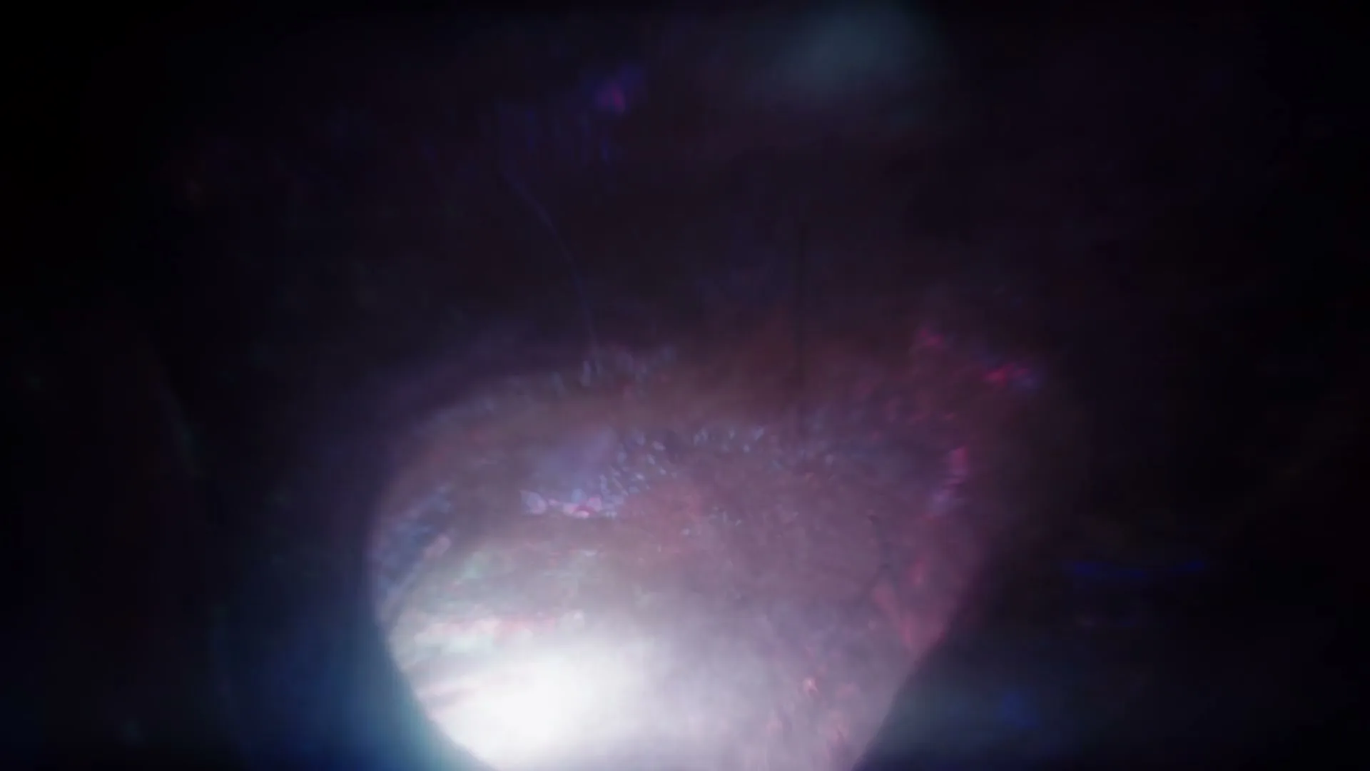 A dark, abstract tunnel with red and blue light, and streaks of light, suggesting a journey through a mysterious space.