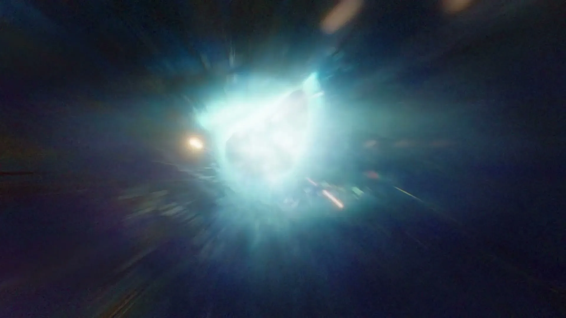 A bright, glowing light with motion blur streaks across the screen, suggesting fast movement through a tunnel or space.