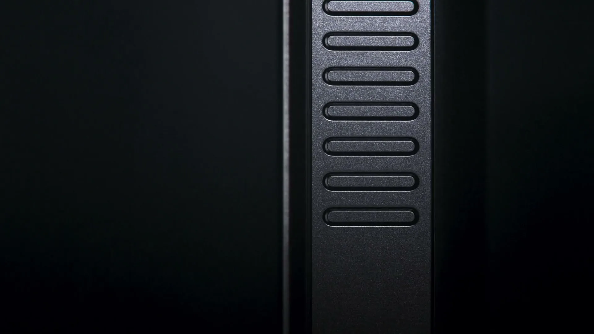 A close-up shot of a black smartphone's side, revealing textured buttons, against a dark background.