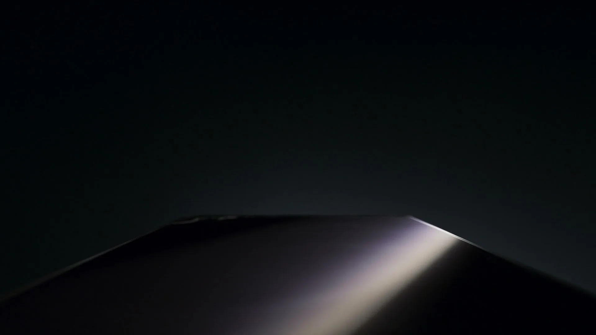 A dark, reflective surface with a subtle light streak moves across the screen, suggesting a car's hood in motion at night.