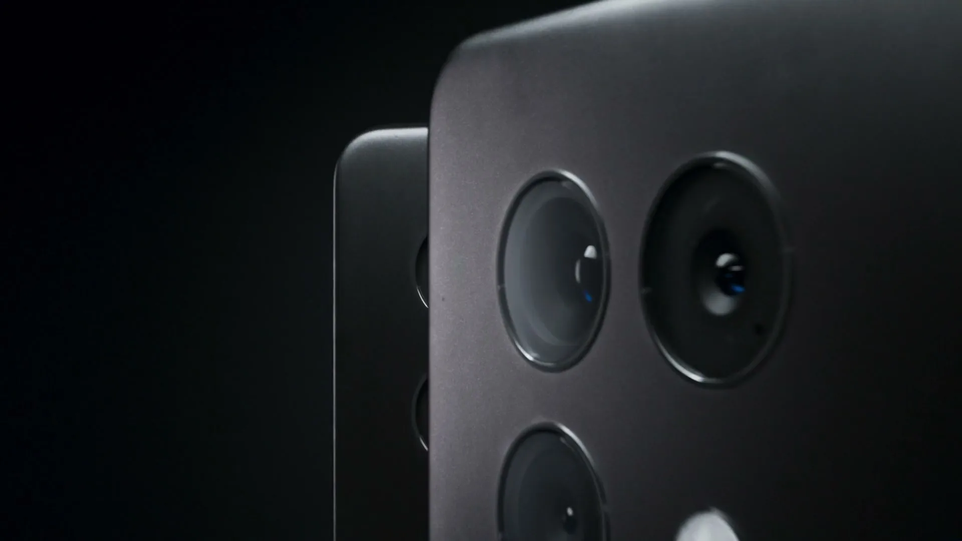 A close-up shot of multiple smartphone cameras on a dark background, with a fingerprint appearing on the phone's surface.
