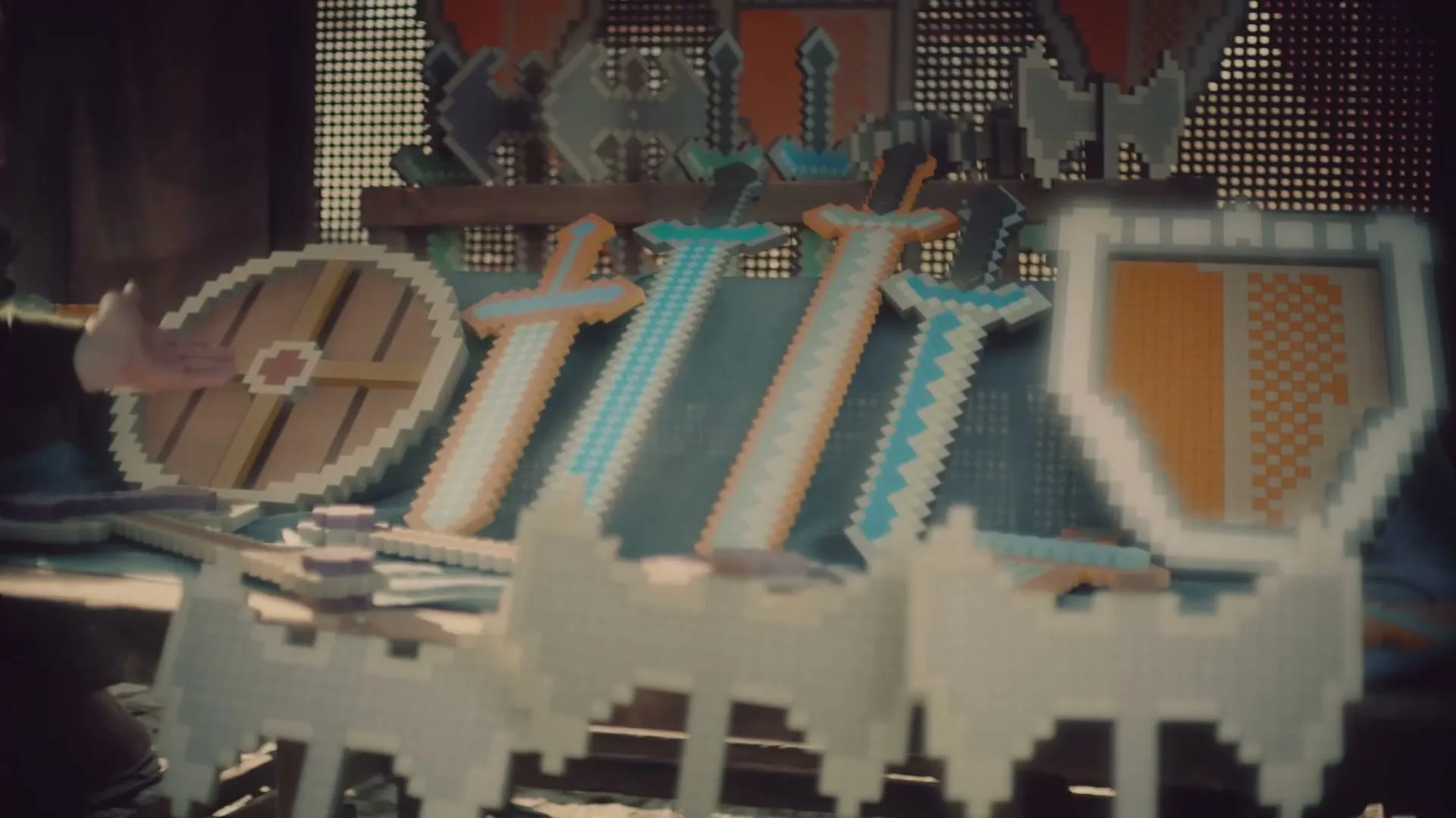 A person's hand reaches out towards a display of pixelated swords and shields in a rustic market stall.