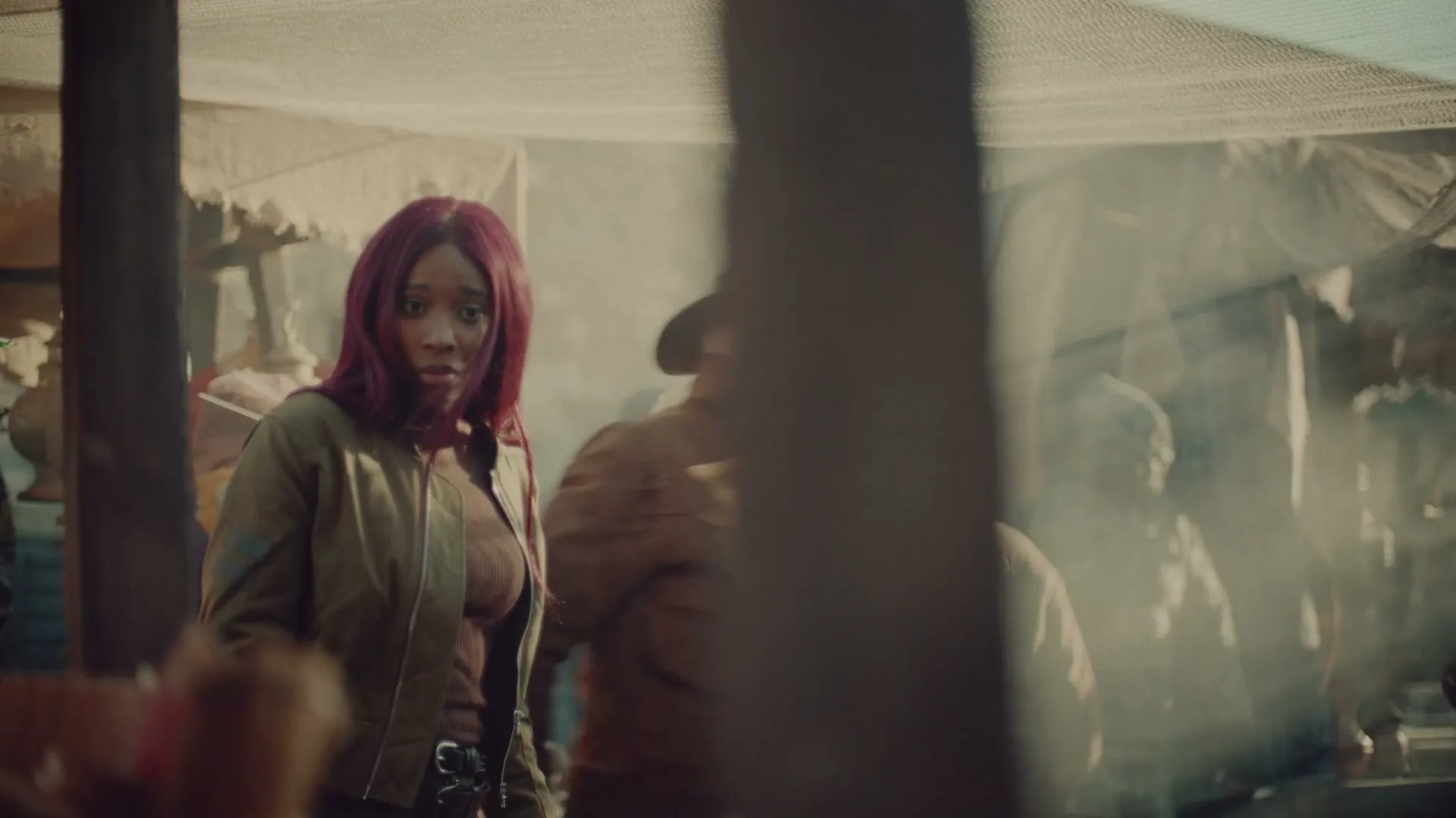 A young woman with red hair and elf ears looks around a bustling, smoky marketplace with a worried expression.