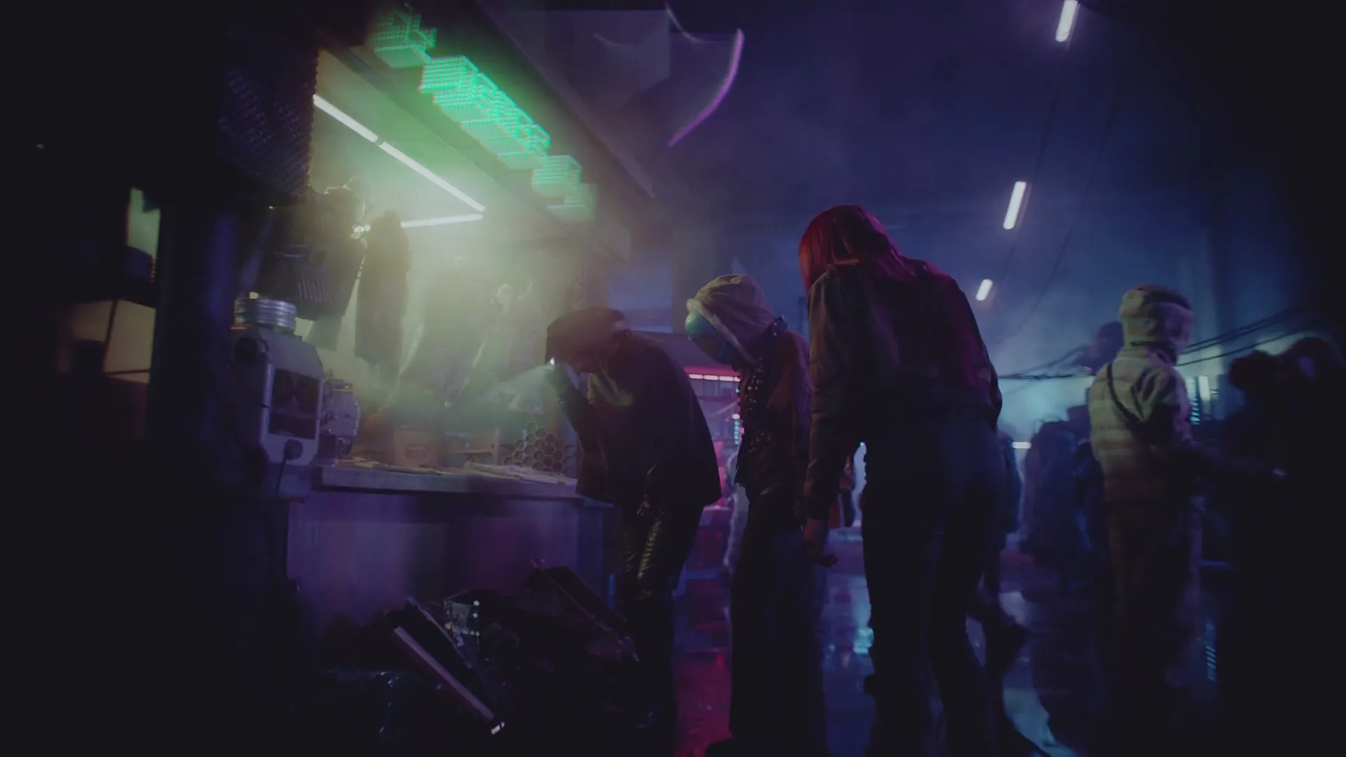 A group of people in a dark, futuristic market look at items on a counter under neon green lights, with a purple glow in the background.