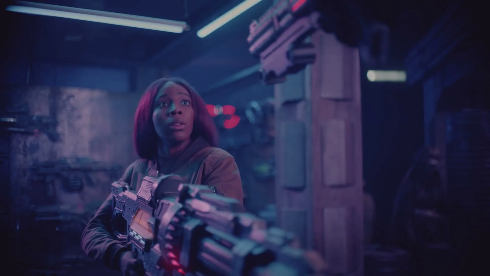 A young Black woman with a futuristic weapon looks around a dark, neon-lit room, appearing surprised or scared.