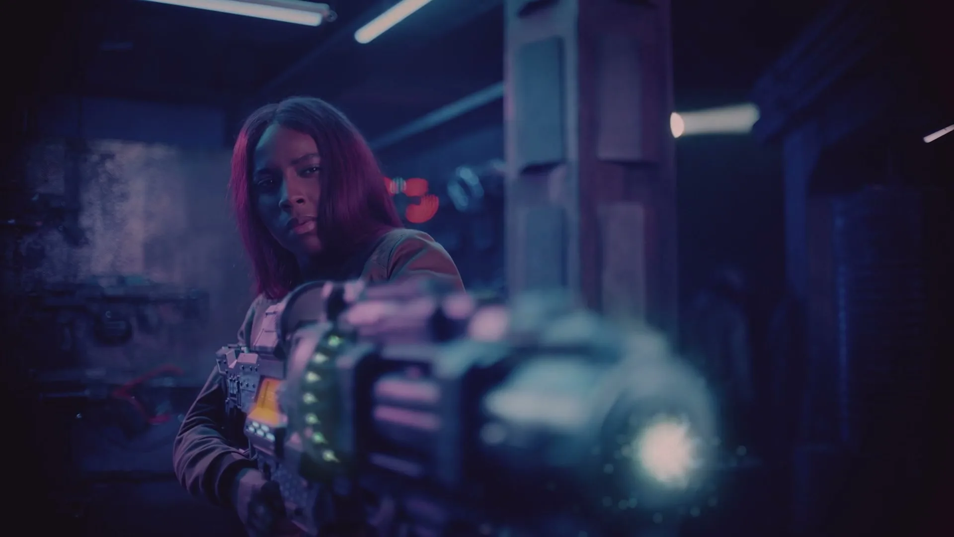A young woman with long red hair holds a large futuristic weapon, looking intently forward in a dark, neon-lit room.