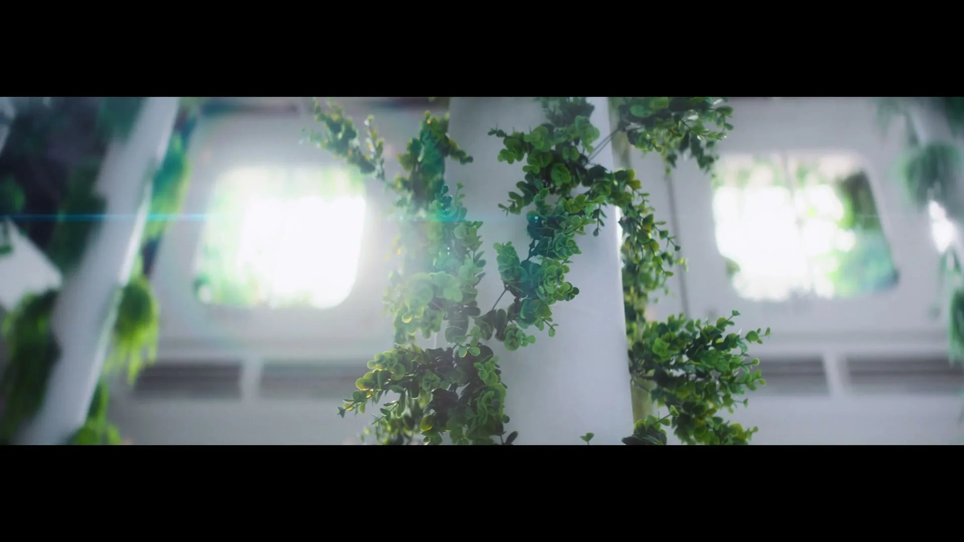 Lush green plants grow on white pillars in a bright, futuristic interior space with glowing windows, suggesting a sustainable environment.