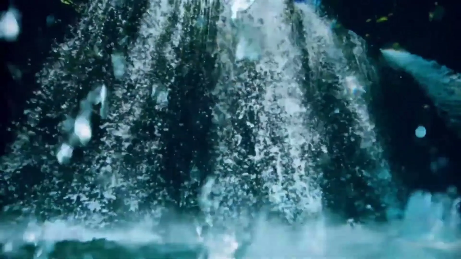 A close-up shot of a waterfall shows water cascading down, creating a misty, dynamic scene in a natural setting.
