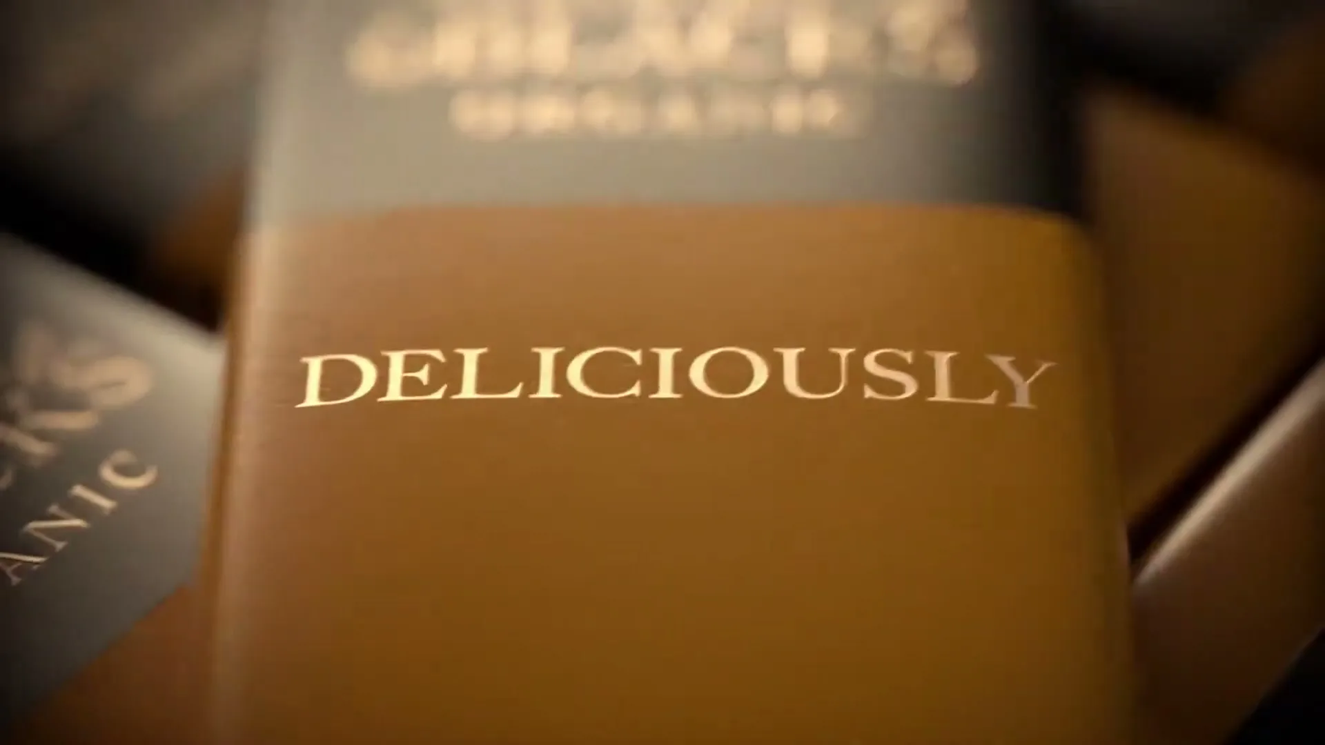 A close-up shot of a Green & Black's chocolate bar with the word "DELICIOUSLY" prominently displayed on its wrapper.