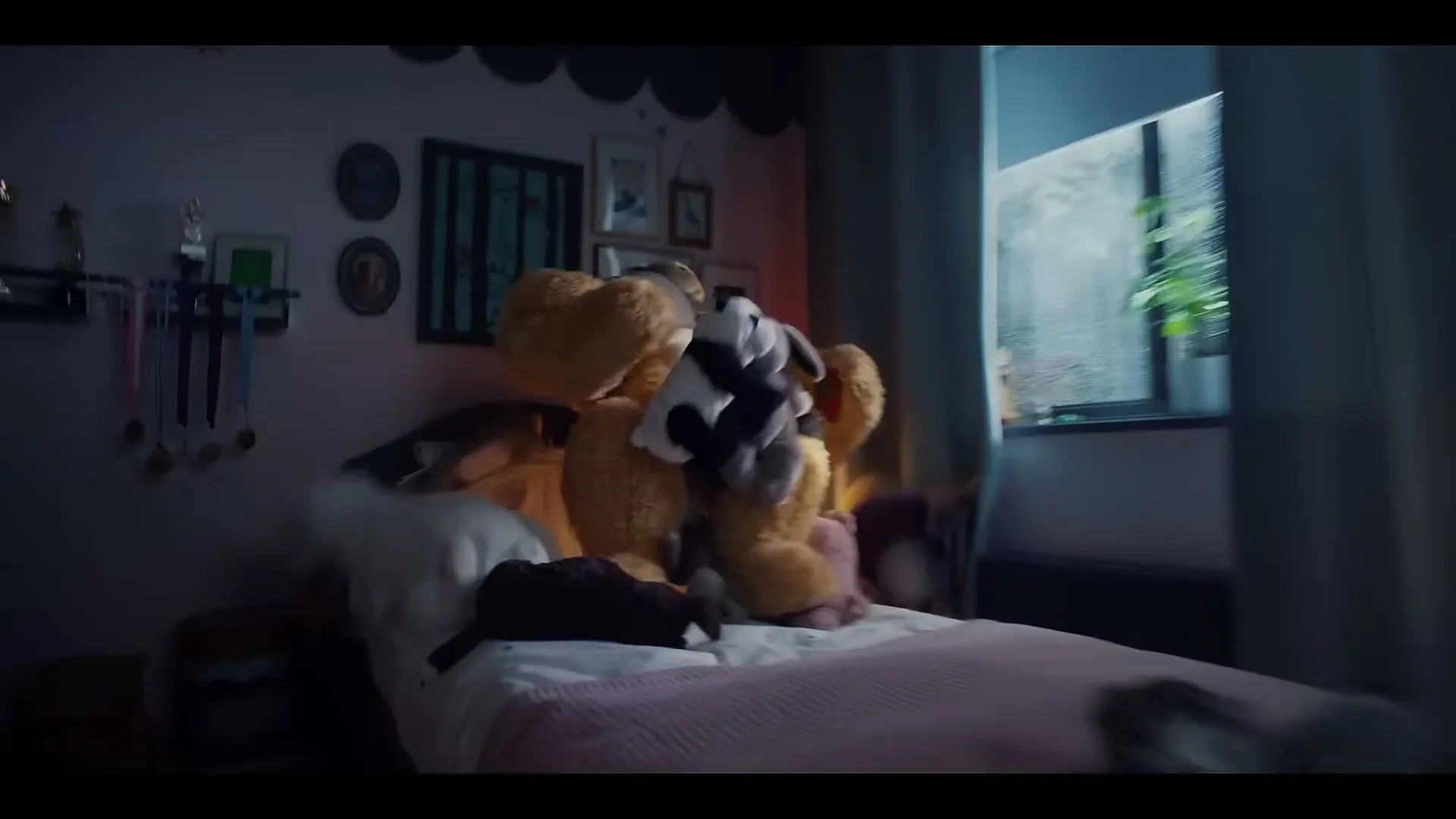 A camera pans right to reveal a muscular teddy bear standing on a bed in a child's bedroom, with a window showing rain outside.