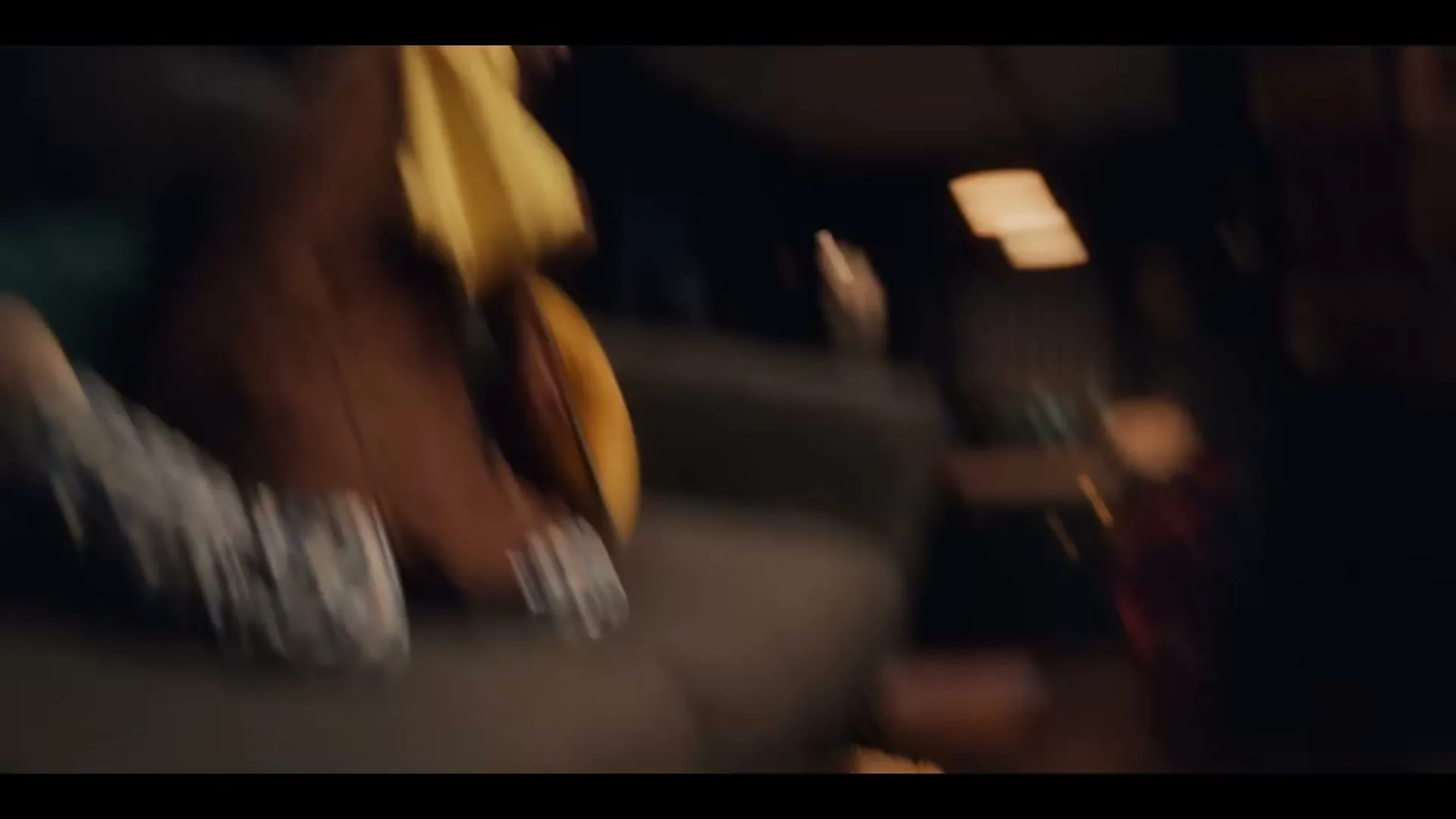 A young Black girl in a yellow shirt and brown overalls plays with a blanket on a couch, then falls off, revealing two teddy bears on the floor.