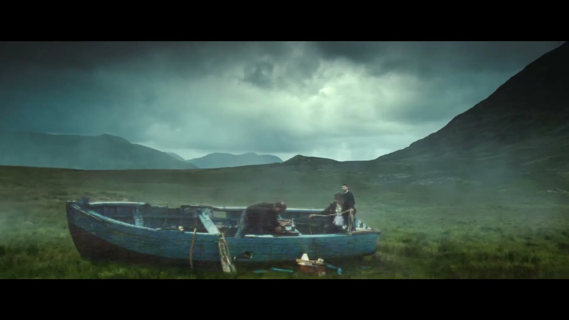 A man in a dark suit walks towards a glitching, old wooden boat in a vast, green field under a cloudy, dramatic sky with mountains in the background.