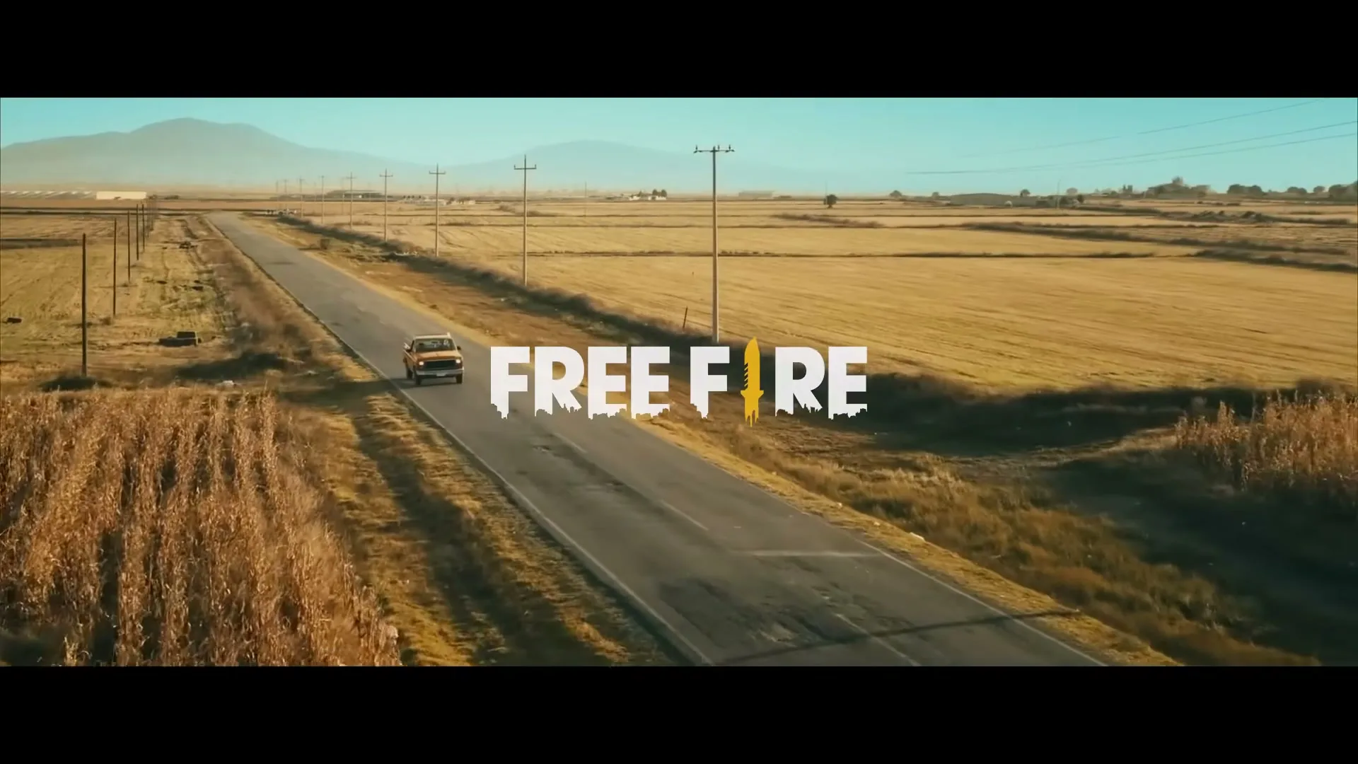 An aerial shot shows a yellow pickup truck driving down a long, empty road through dry fields under a clear sky, with "FREE FIRE" text overlaid.
